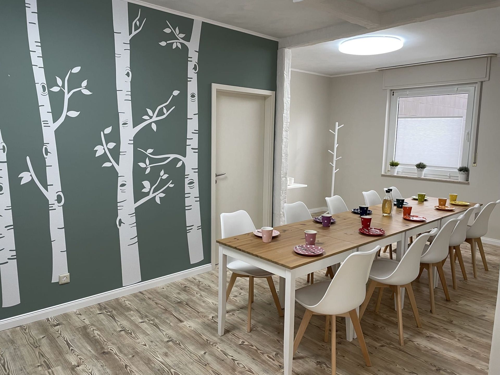 Ein Esszimmer mit Tisch und Stühlen und Bäumen an der Wand.