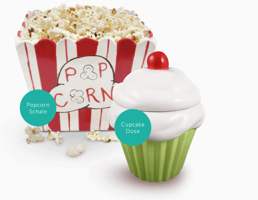 Ein Cupcake mit einer Kirsche obendrauf neben einer Schachtel Popcorn