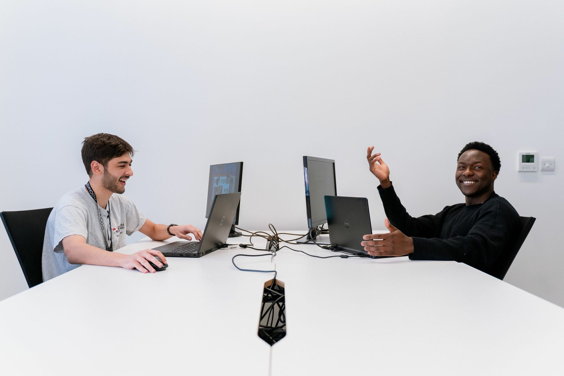 two people on laptops sitting at a desk
