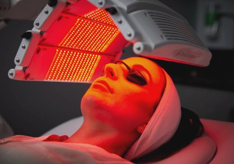 A woman is getting a red light treatment on her face.