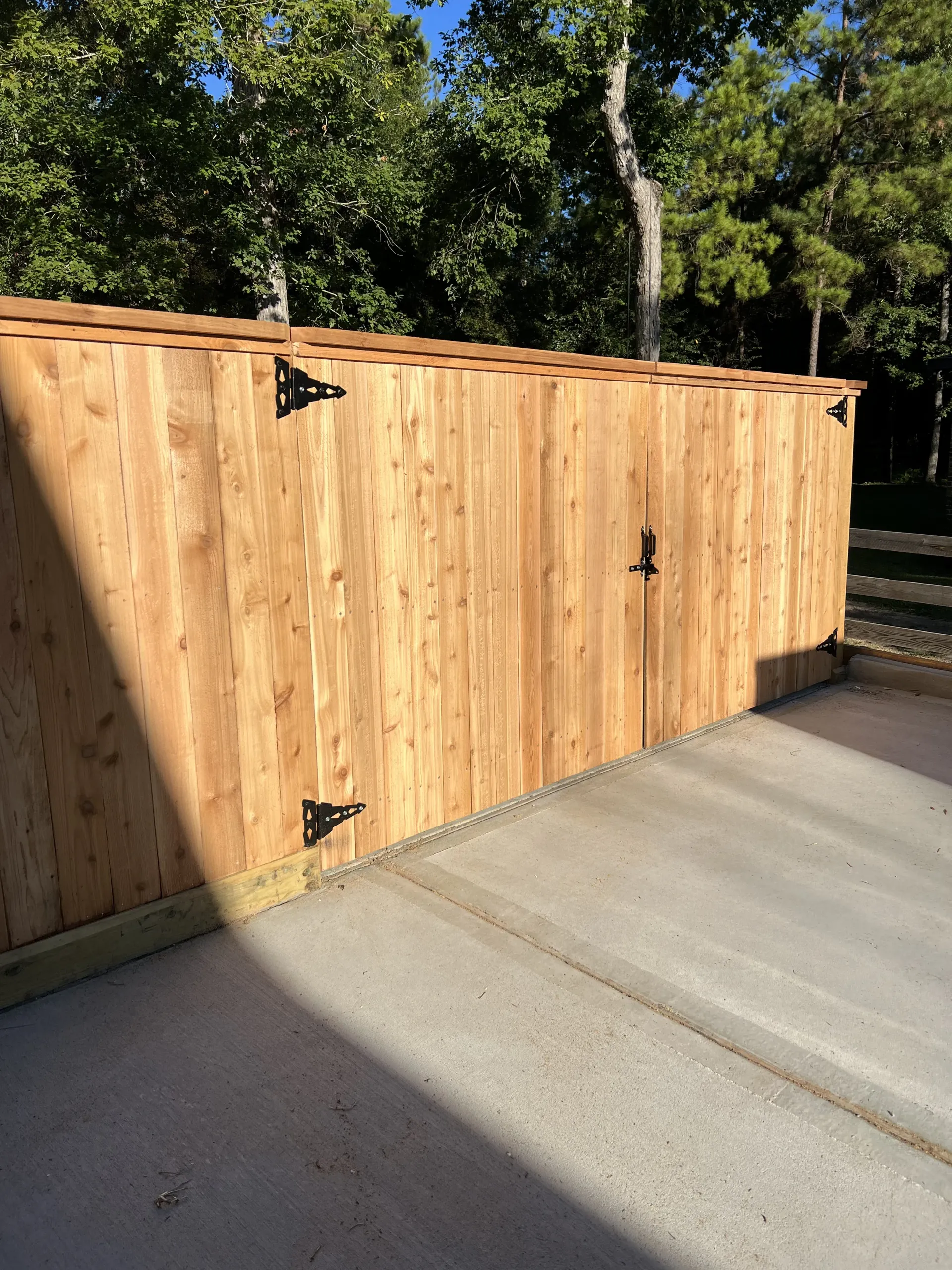 Professional cedar fence installation with double gate and natural wood finish