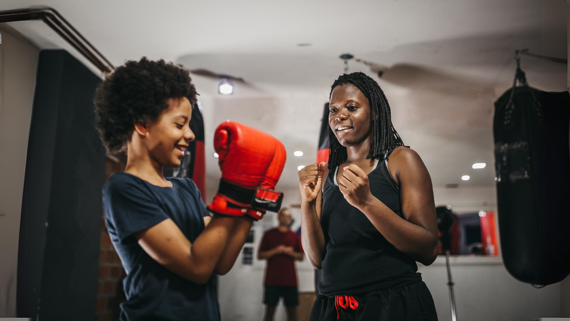 A woman and a boy are boxing in a gym.