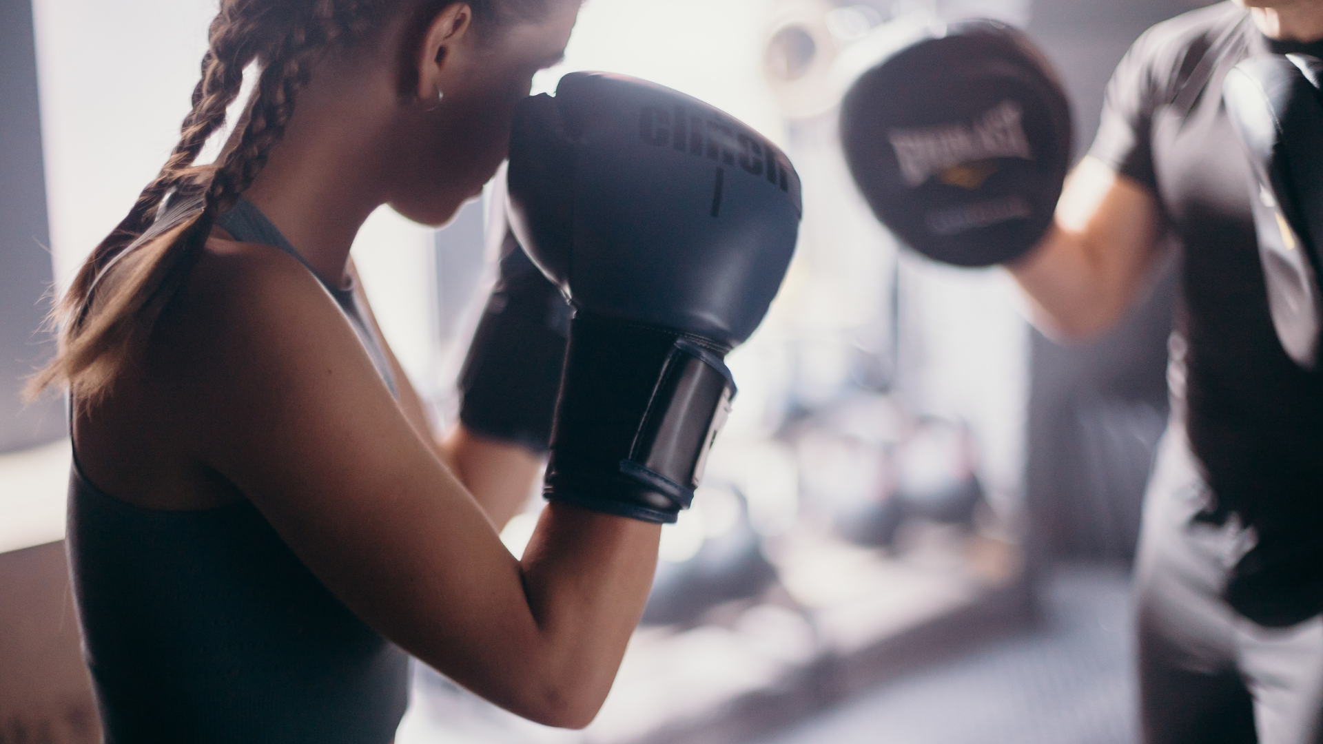 A man wearing boxing gloves is standing in front of a white brick wall.