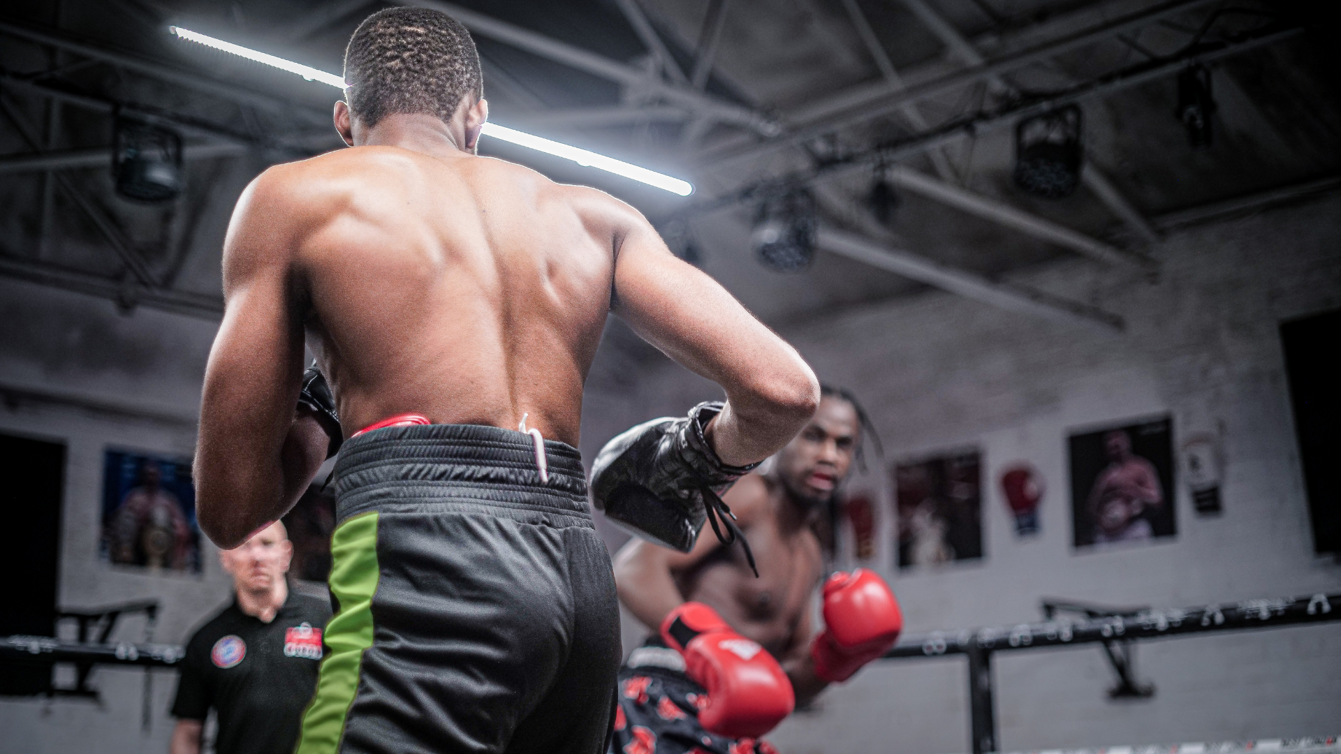 Two boxers in a training session, with one facing away while the other is preparing to strike, set i