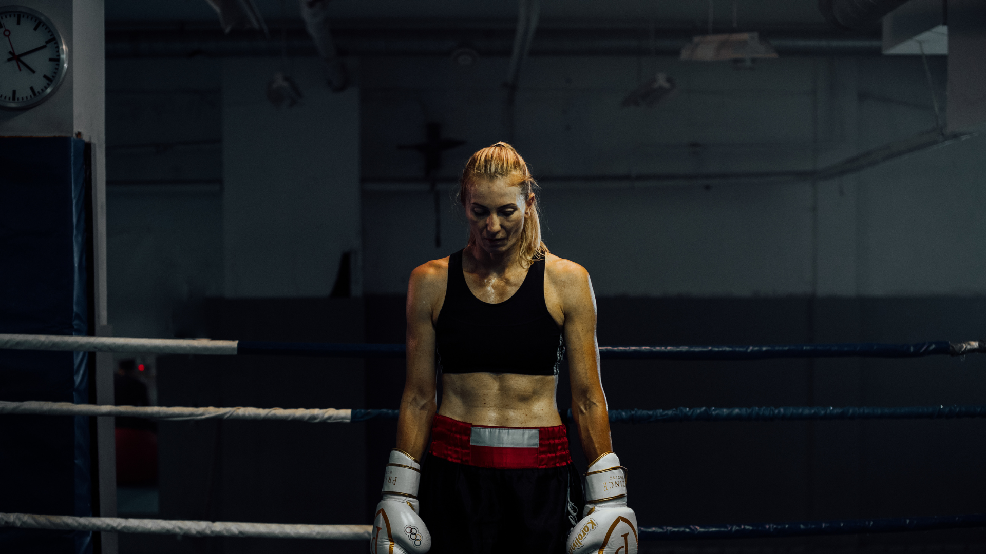 A man wearing boxing gloves is standing in front of a white brick wall.