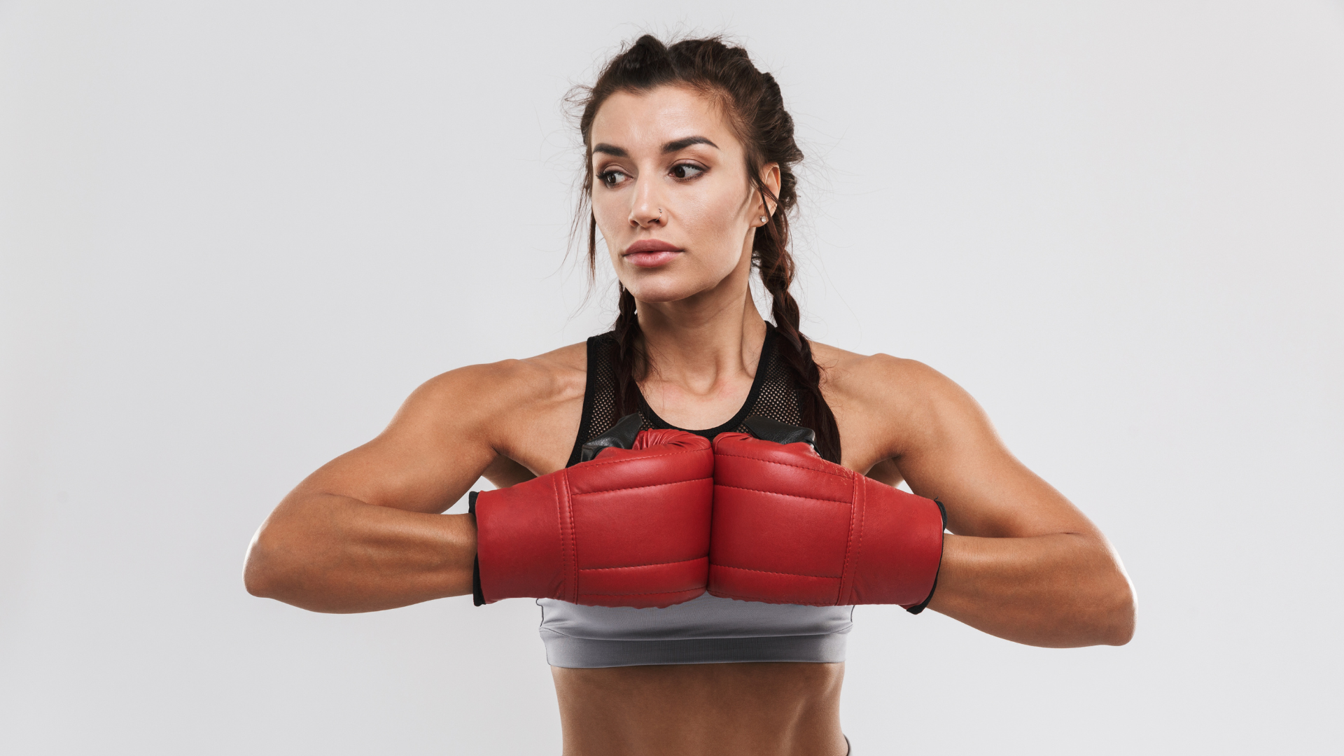 A woman is wearing red boxing gloves and braids.