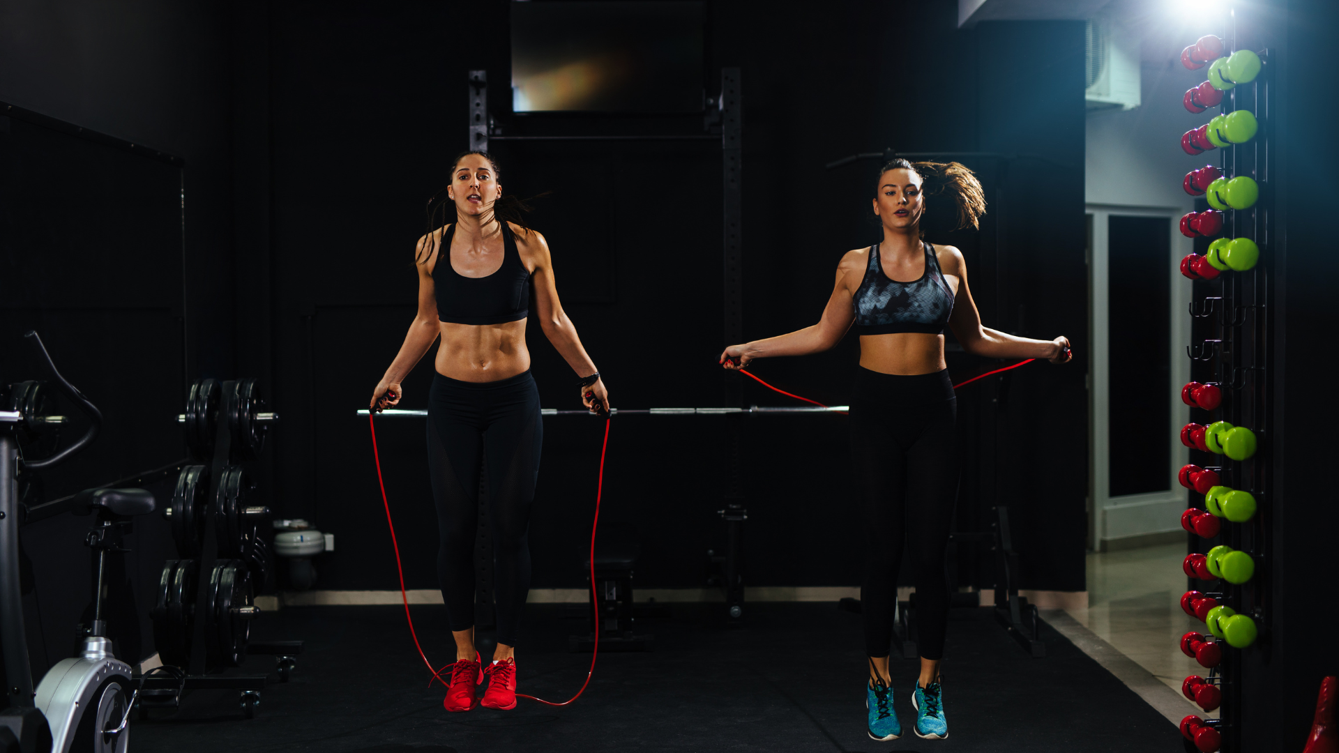 Two women are jumping rope in a gym.