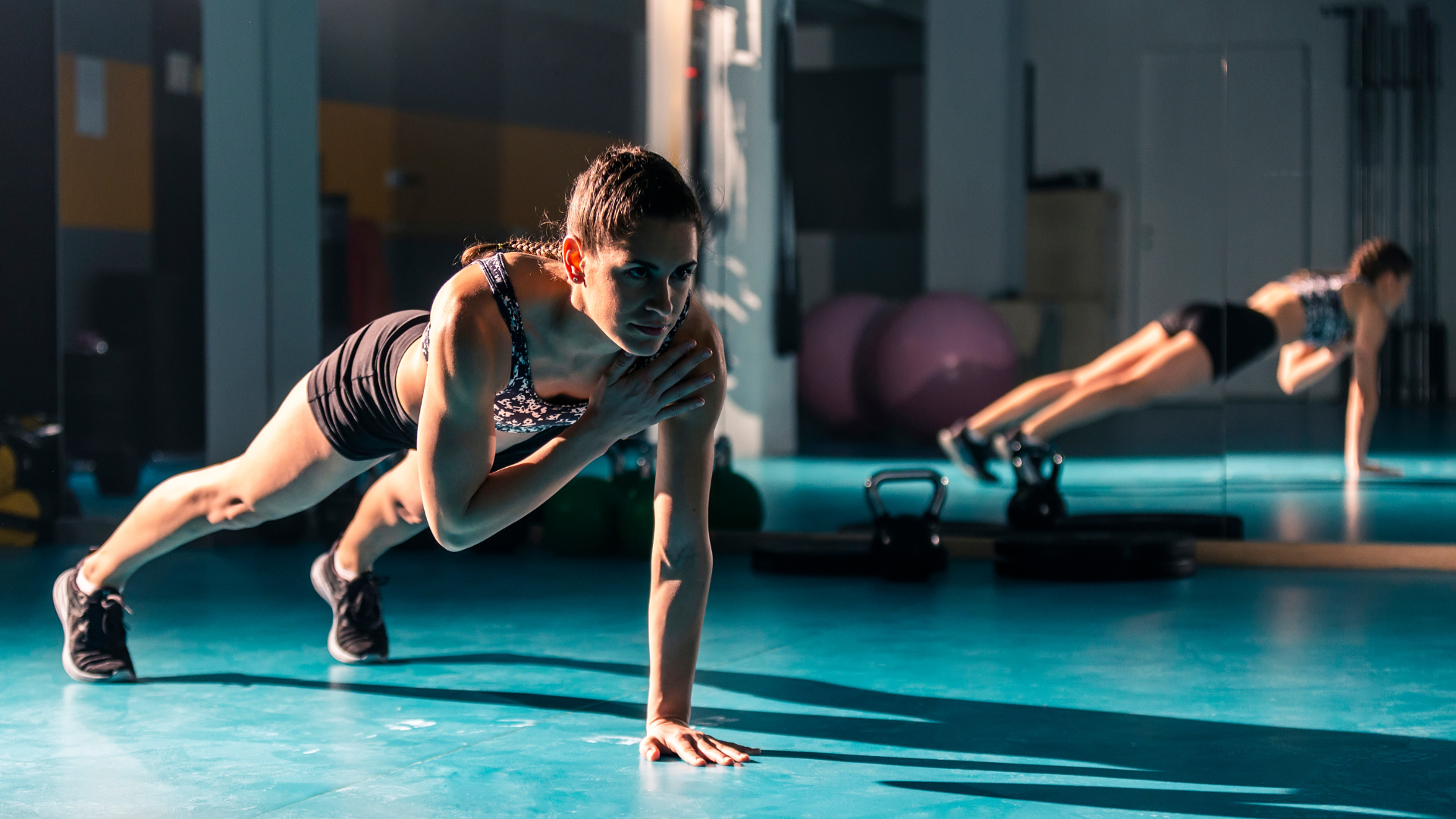 Two women are doing push ups in a gym.
