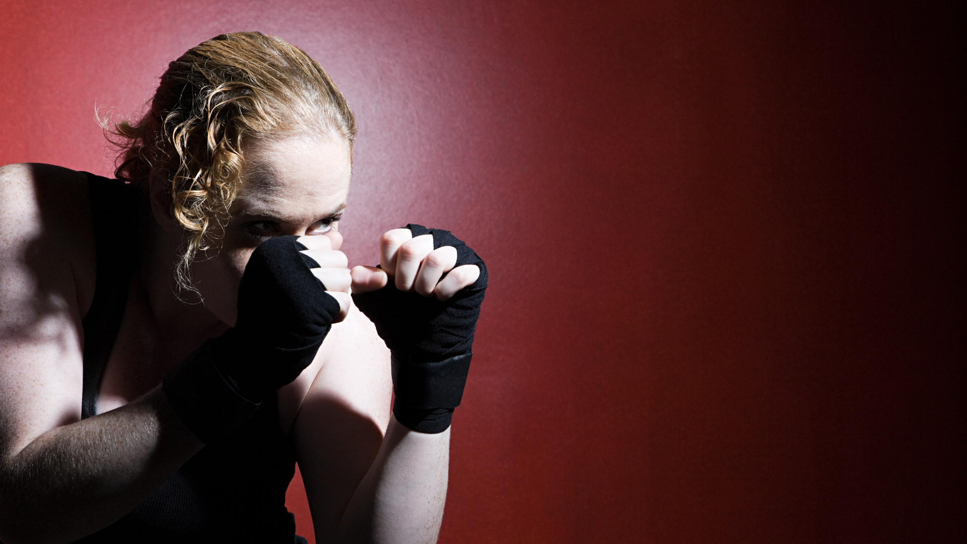 A man wearing boxing gloves is standing in front of a white brick wall.