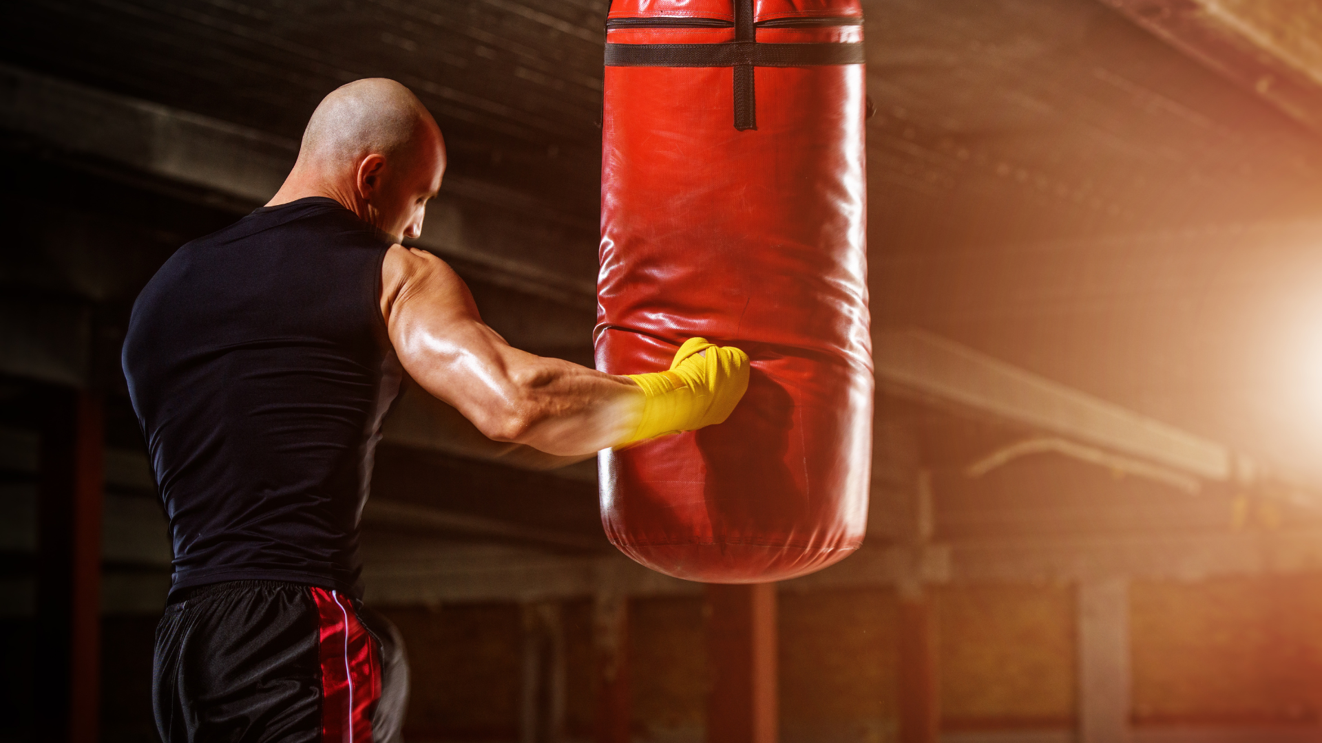 A man is hitting a boxing bag in a gym.