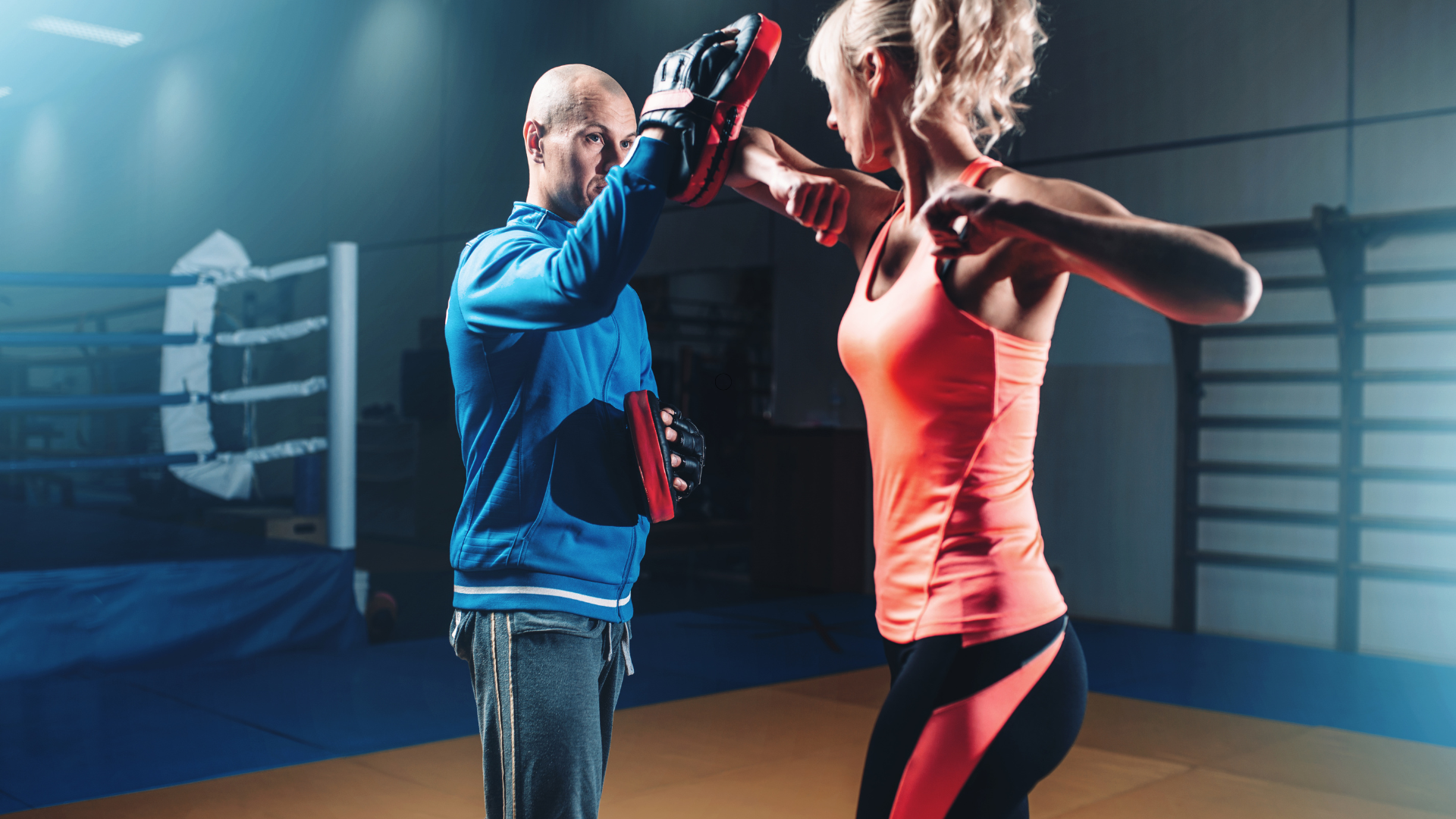 A man and a woman are boxing in a gym.