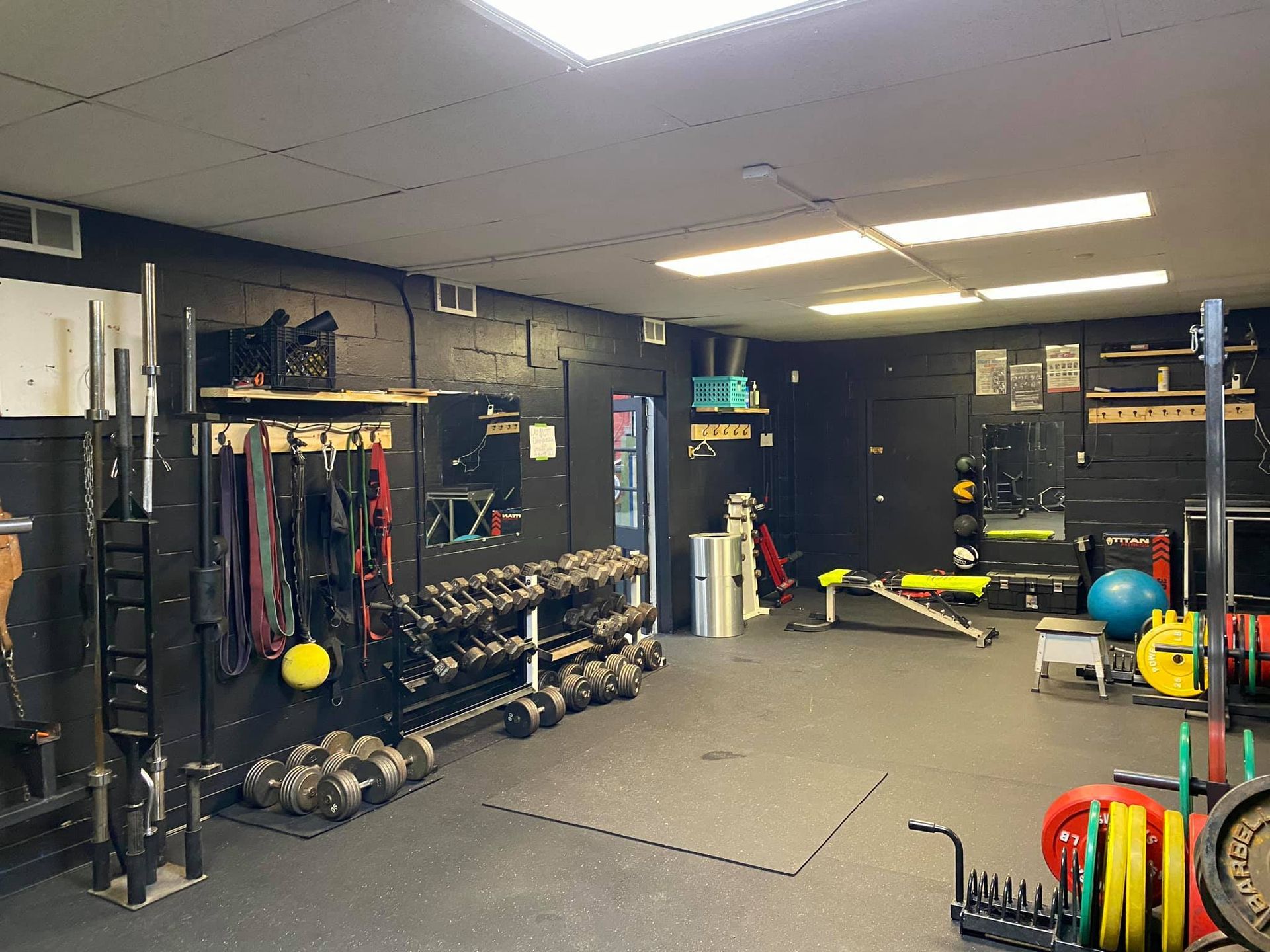 a gym filled with lots of dumbbells , barbells , and other exercise equipment .