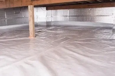 Crawlspace with standing water under a wooden floor, showing flood damage