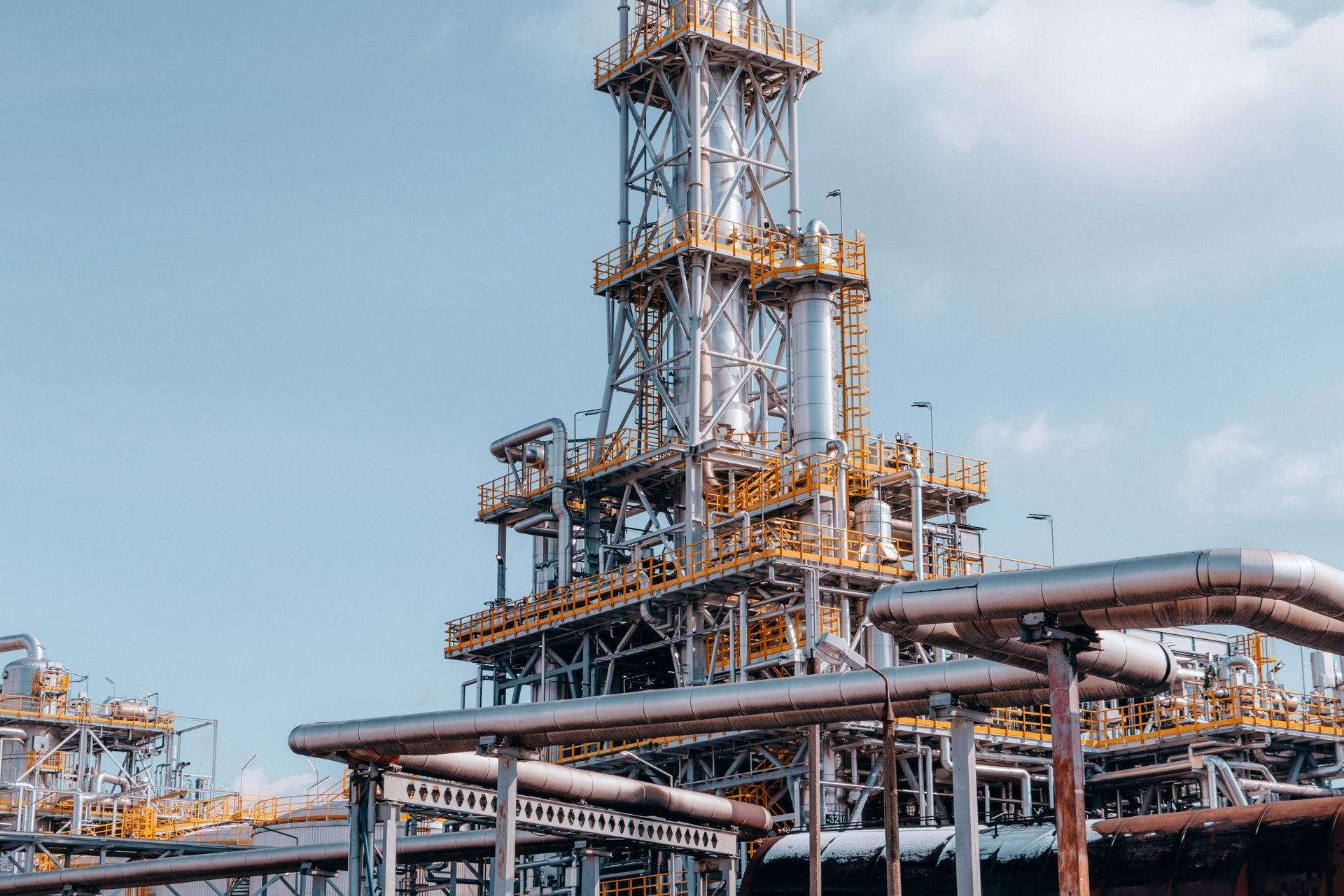 Industrial plant with pipes, towers, and tanks against a blue sky.
