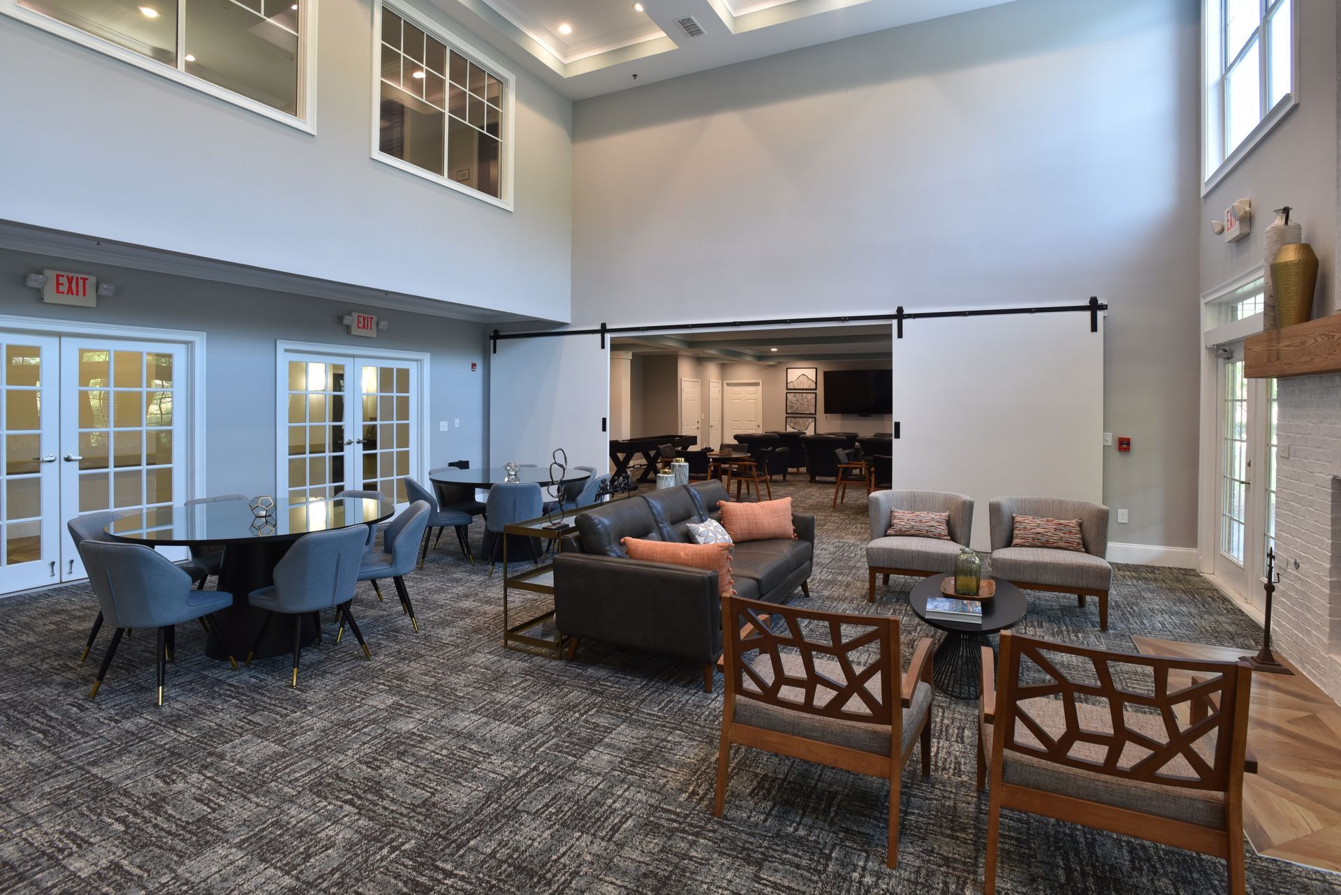 Bright modern dining room with tables, chairs, large windows, and a high coffered ceiling.