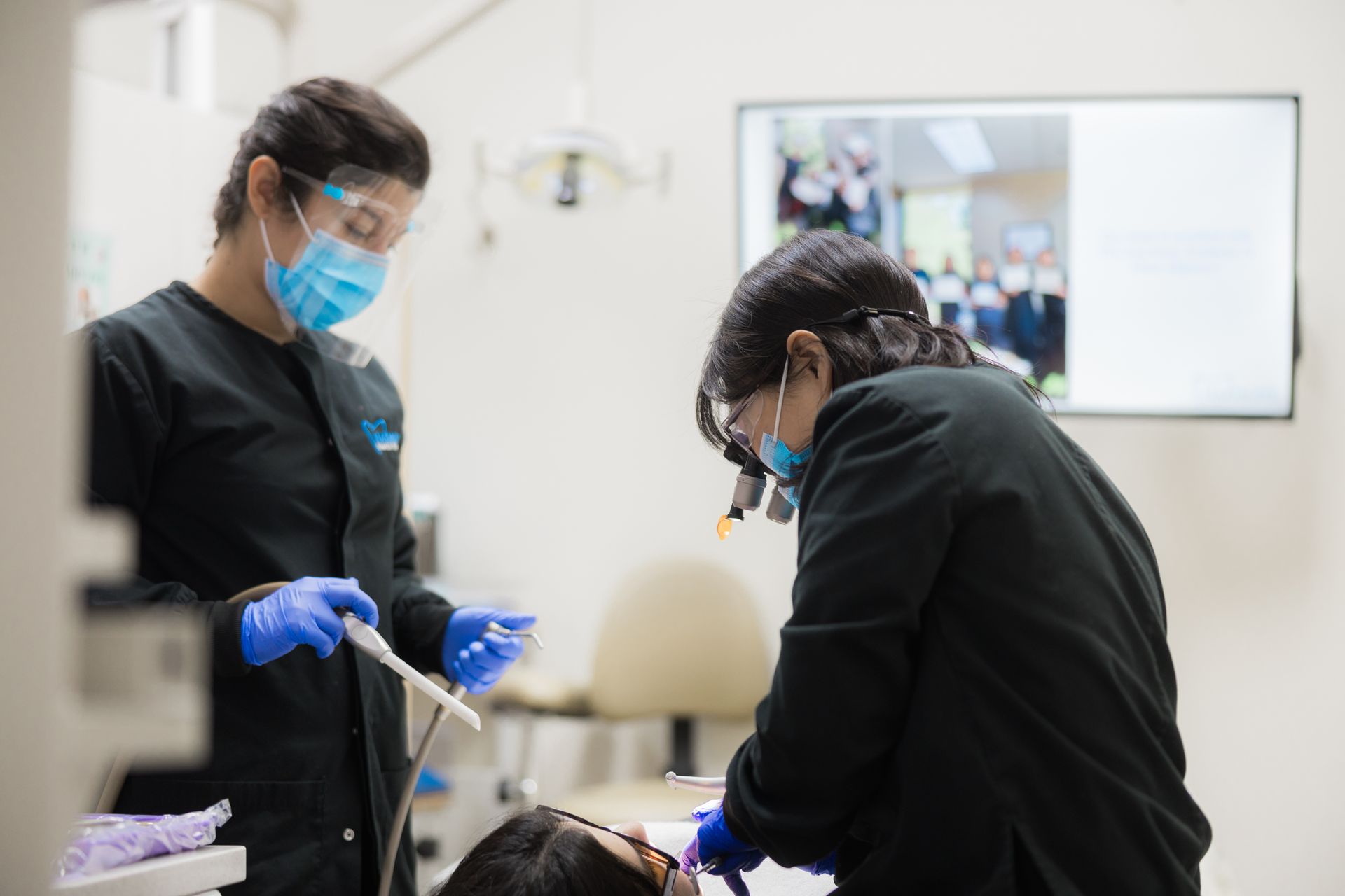 A woman is sitting in a dental chair getting her teeth examined by a dentist.
