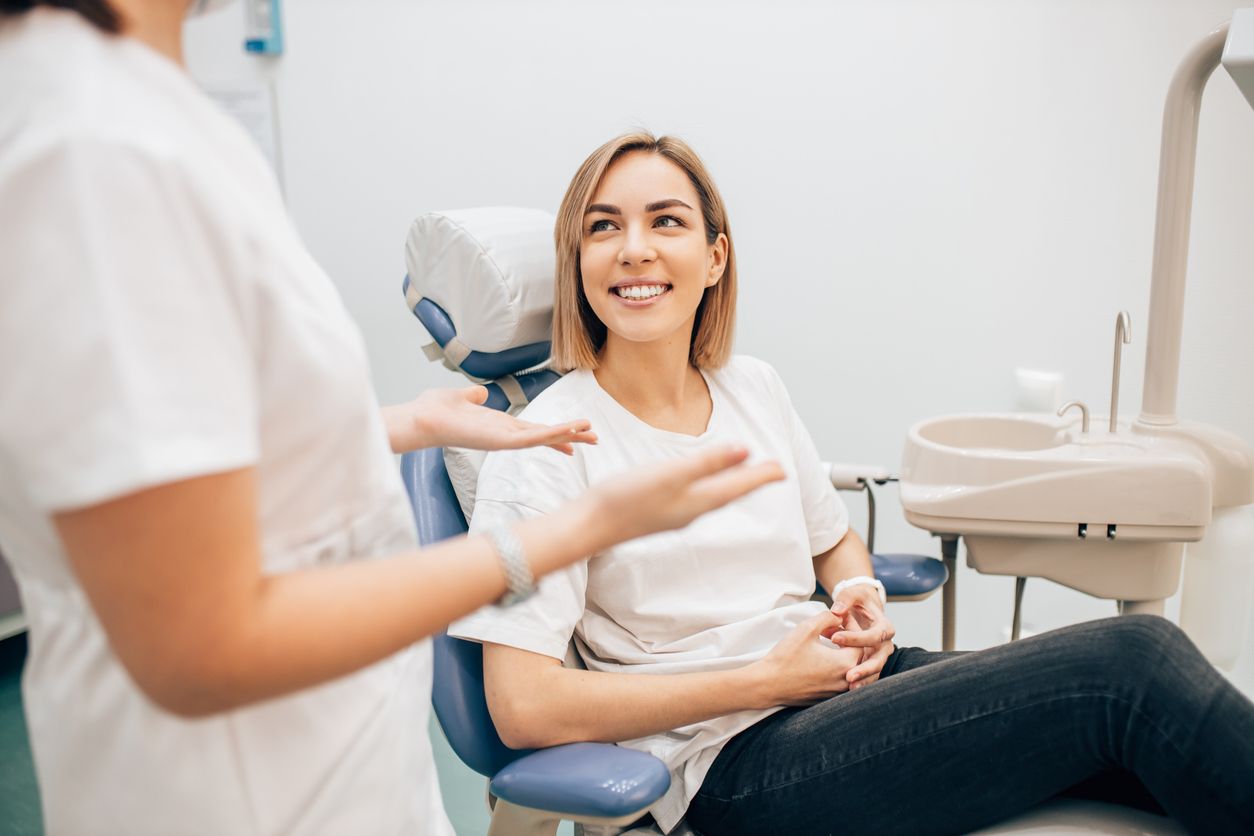A woman is sitting in a dental chair getting her teeth examined by a dentist.