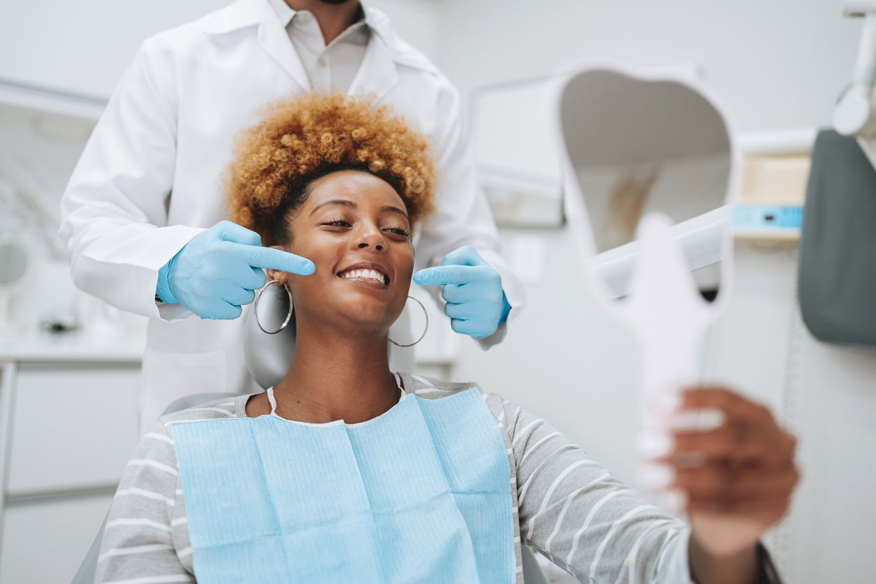 A woman is sitting in a dental chair getting her teeth examined by a dentist.