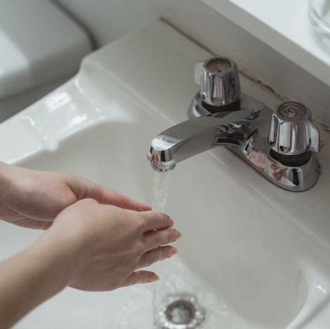 A person is washing their hands in a bathroom sink.