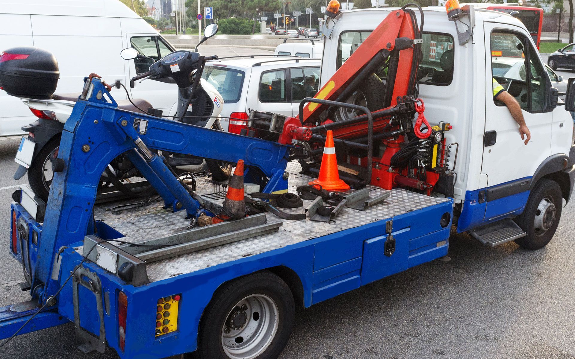 A blue and white tow truck is towing a motorcycle.