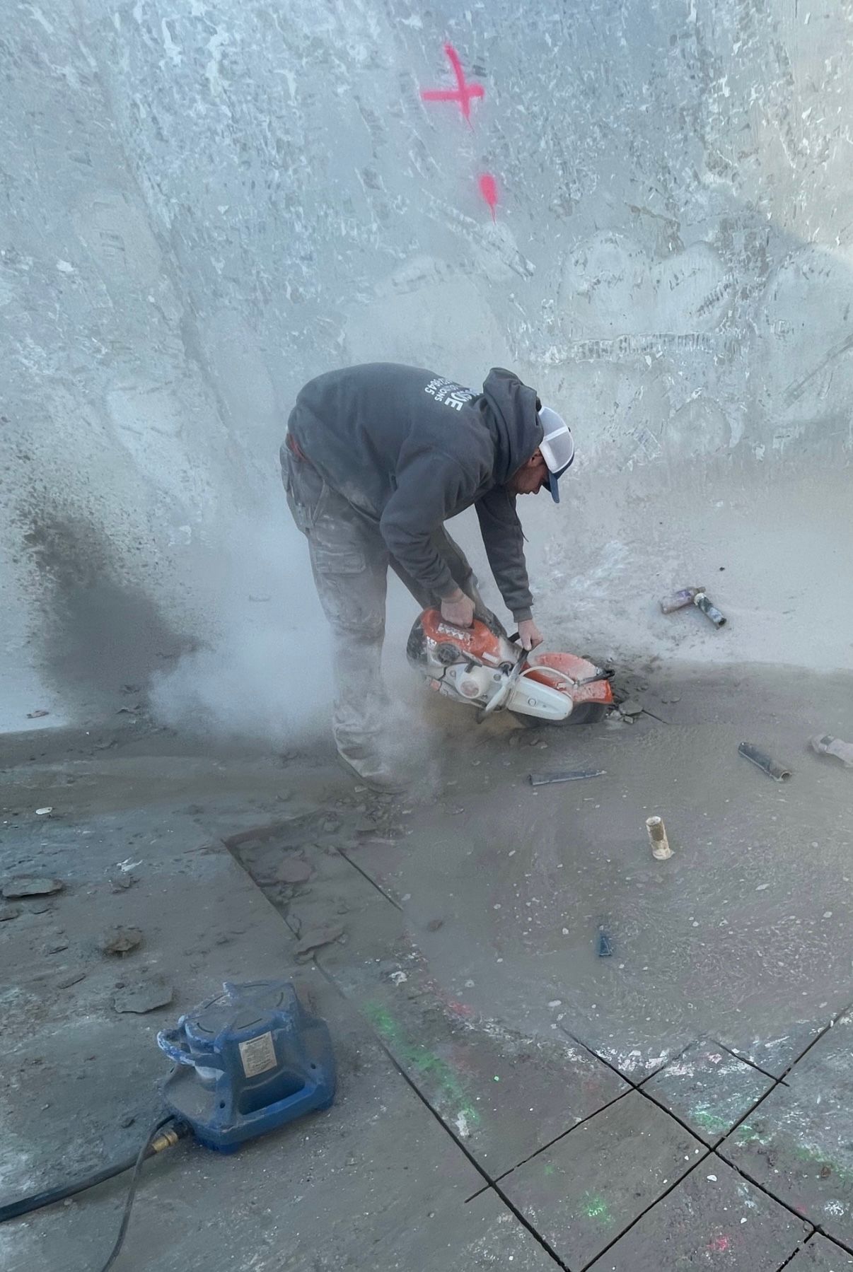 A man is cutting concrete with a circular saw on a sidewalk.