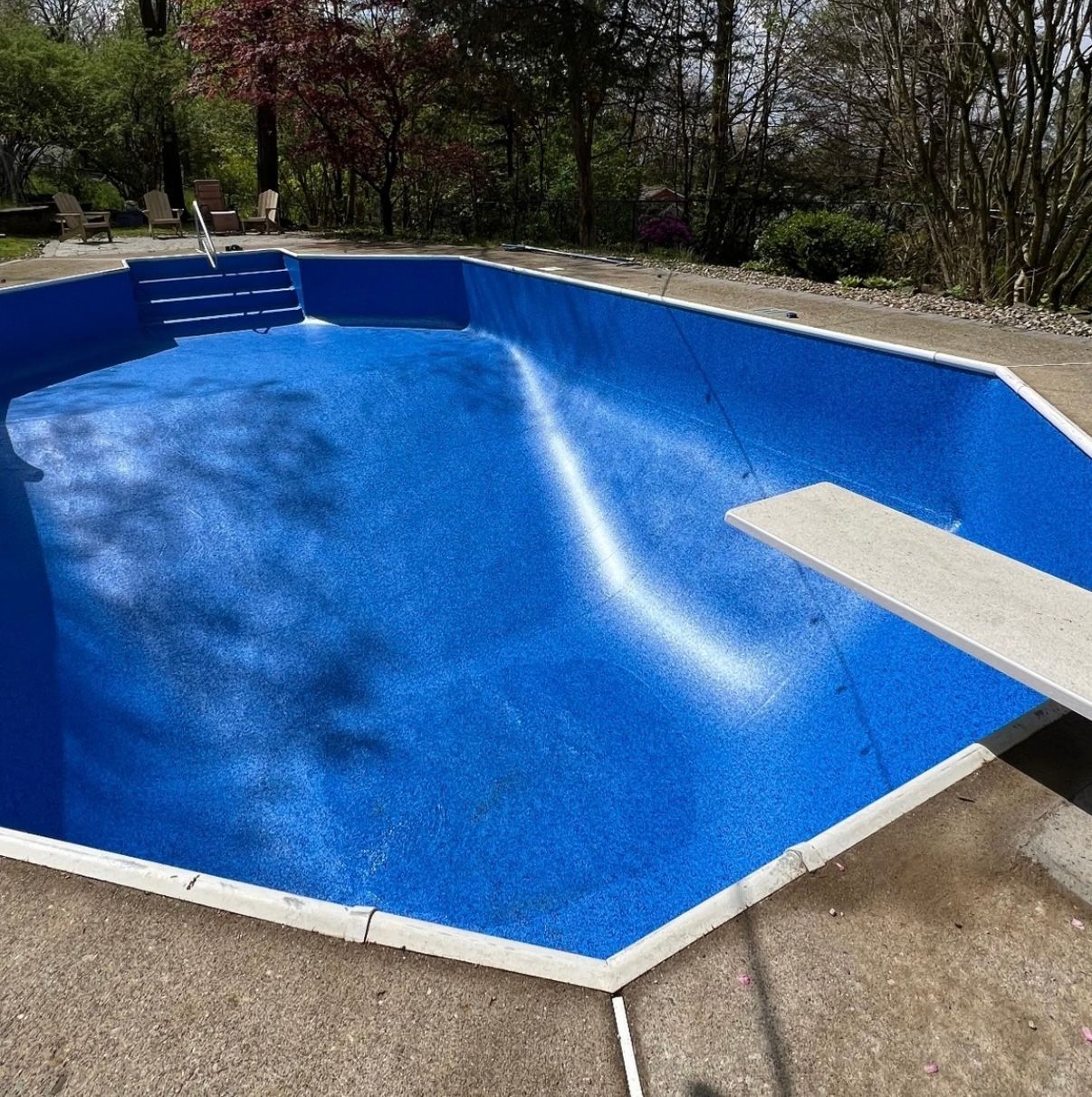 A large blue swimming pool with a diving board in the middle
