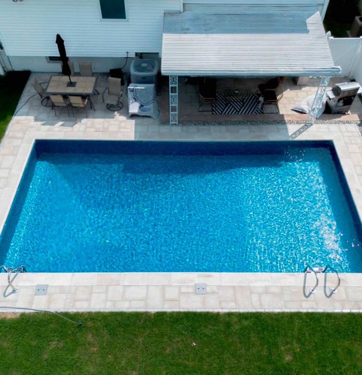 An aerial view of a large swimming pool in front of a house