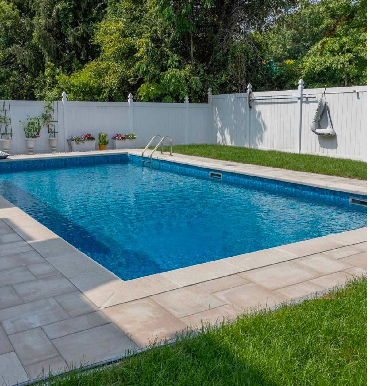 A large swimming pool with a white fence surrounding it