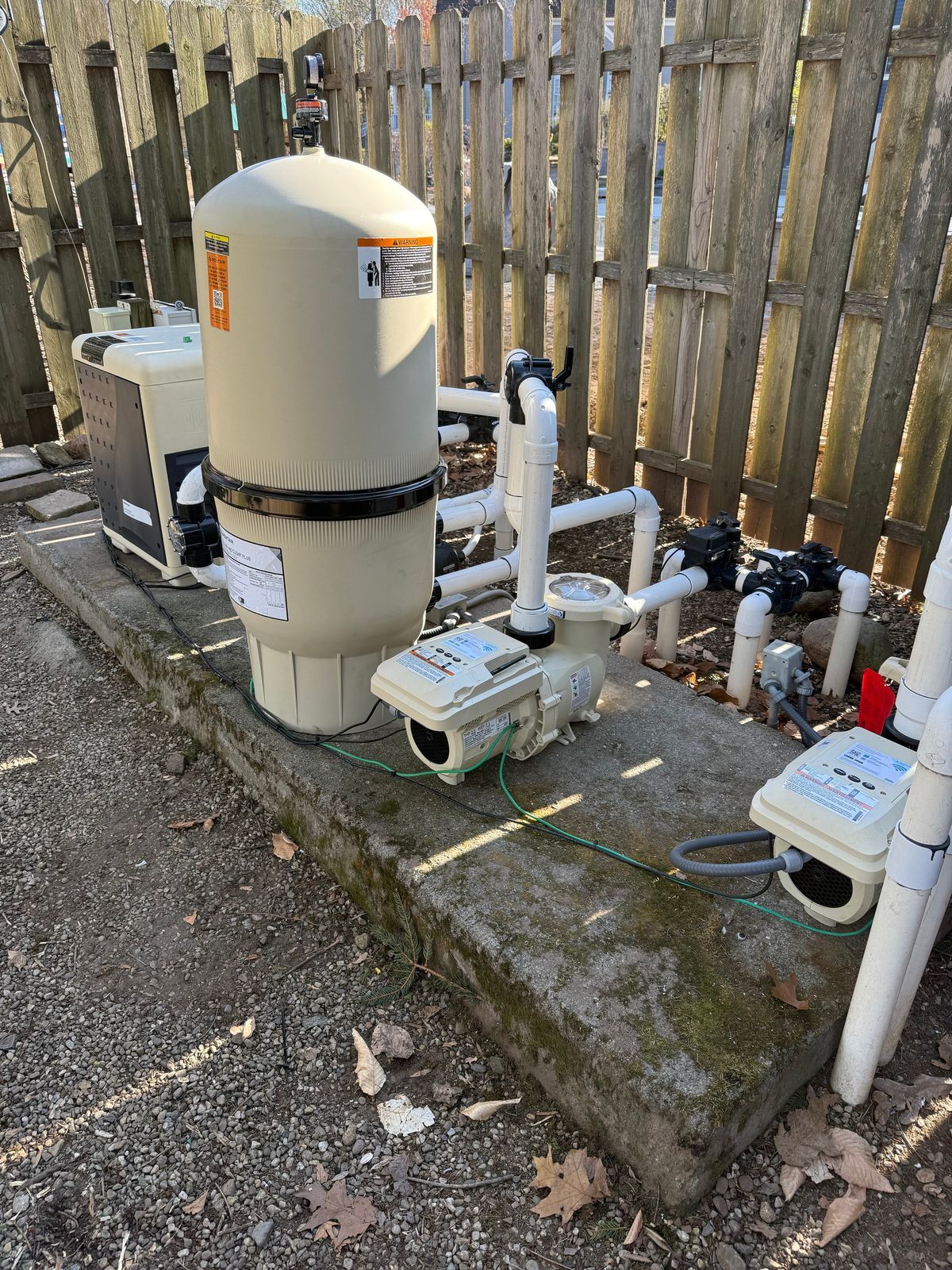 A swimming pool filter is sitting next to a wooden fence.