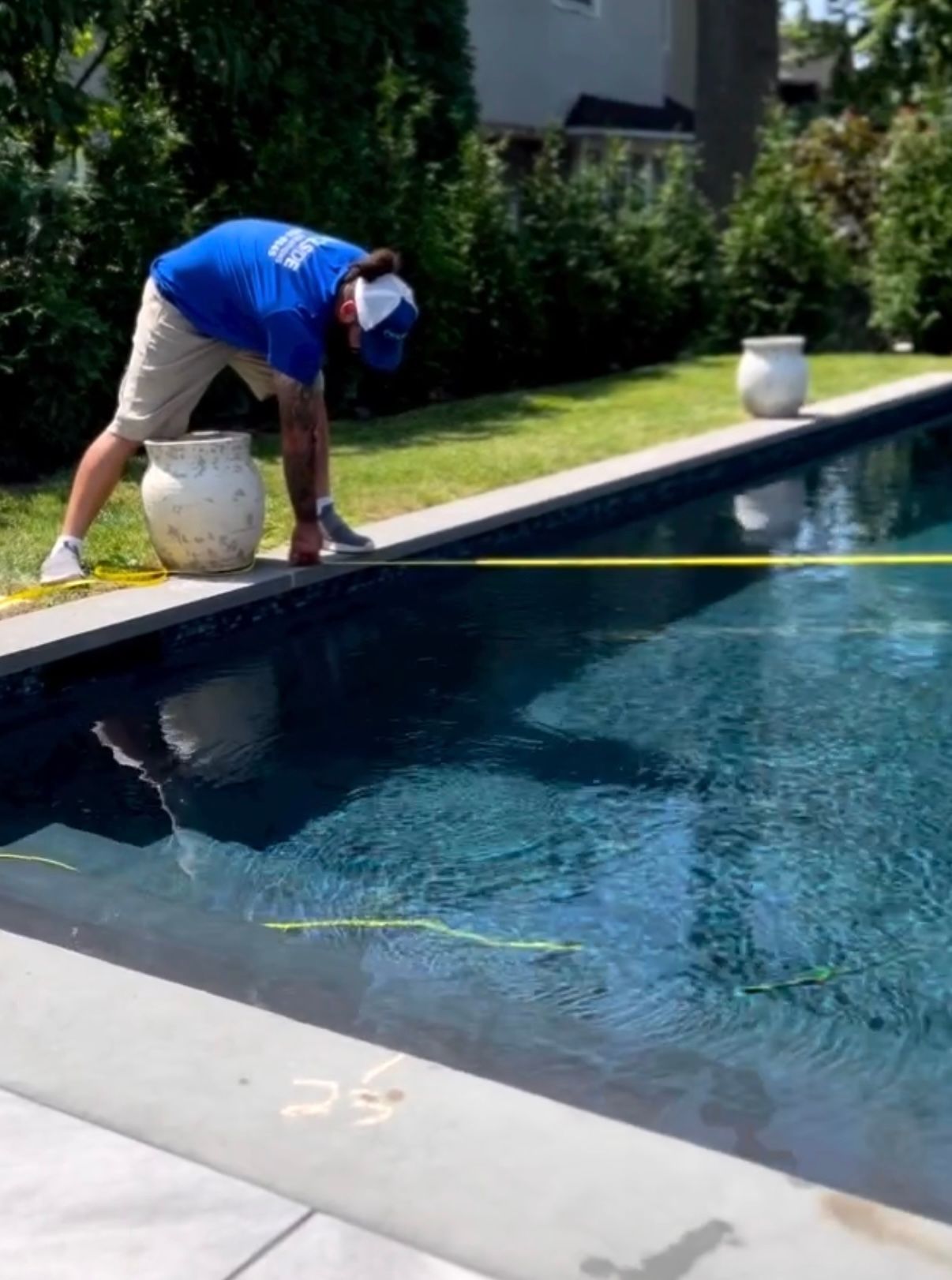 A man is measuring a swimming pool with a tape measure