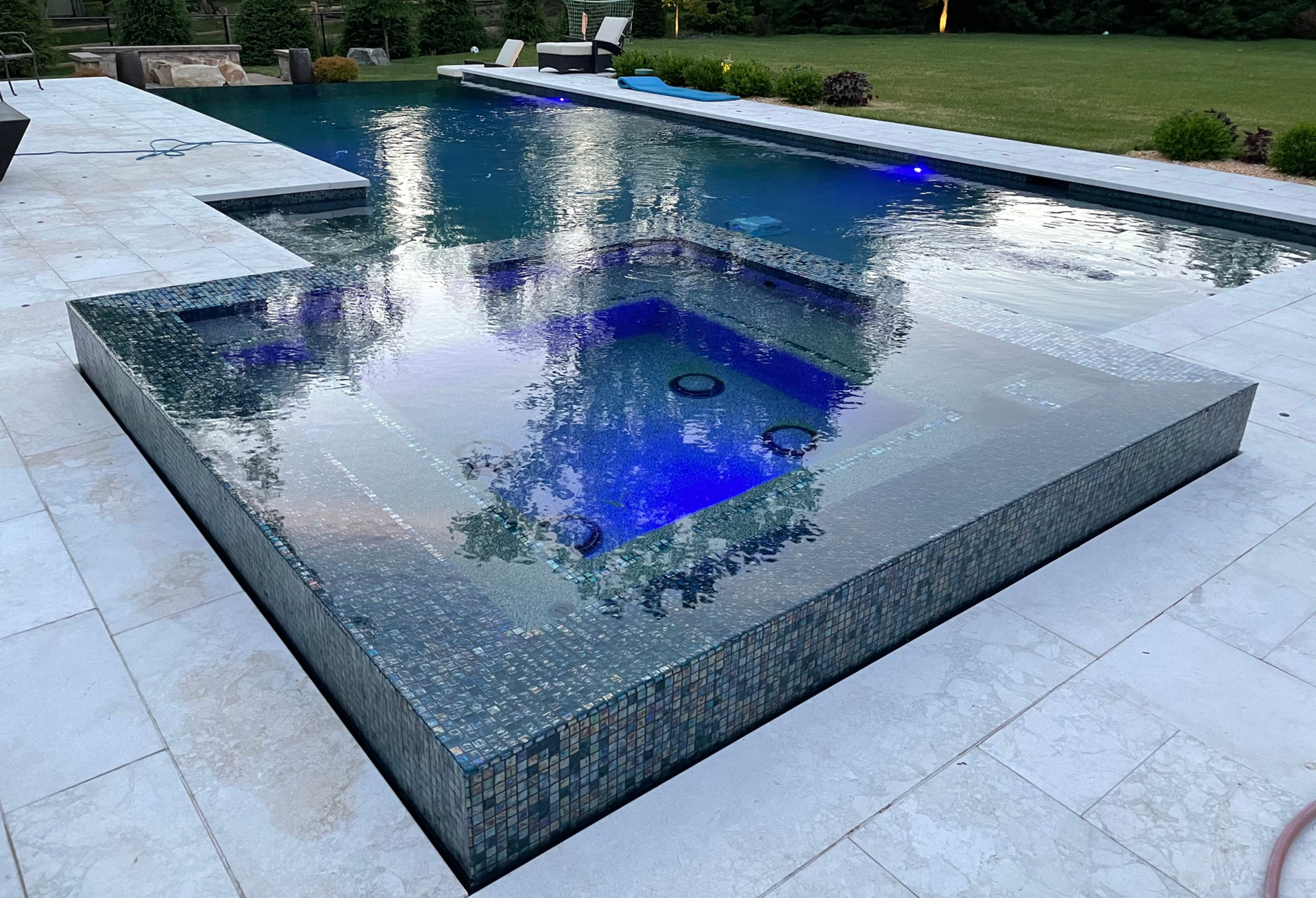 A large swimming pool with a hot tub in the middle of it