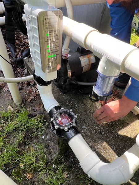 A person is working on a pipe with a thermometer attached to it.