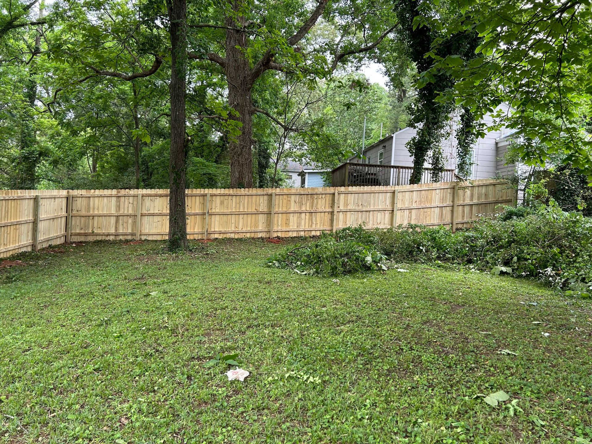 A wooden fence surrounds a lush green yard.