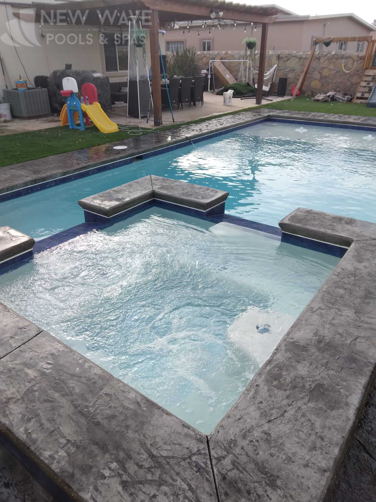 A large swimming pool with a hot tub in the middle of it.