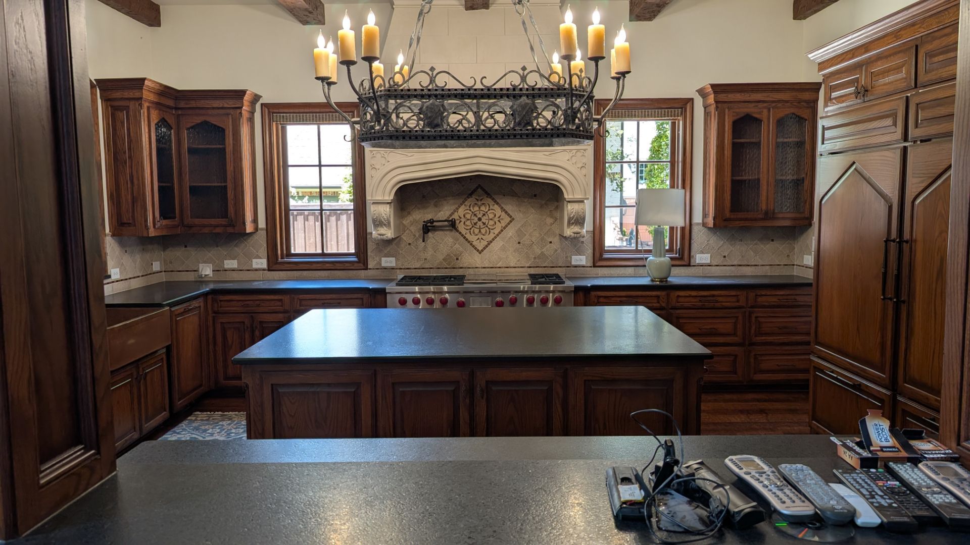 Kitchen with dark wooden cabinets, island, and decorative chandelier.