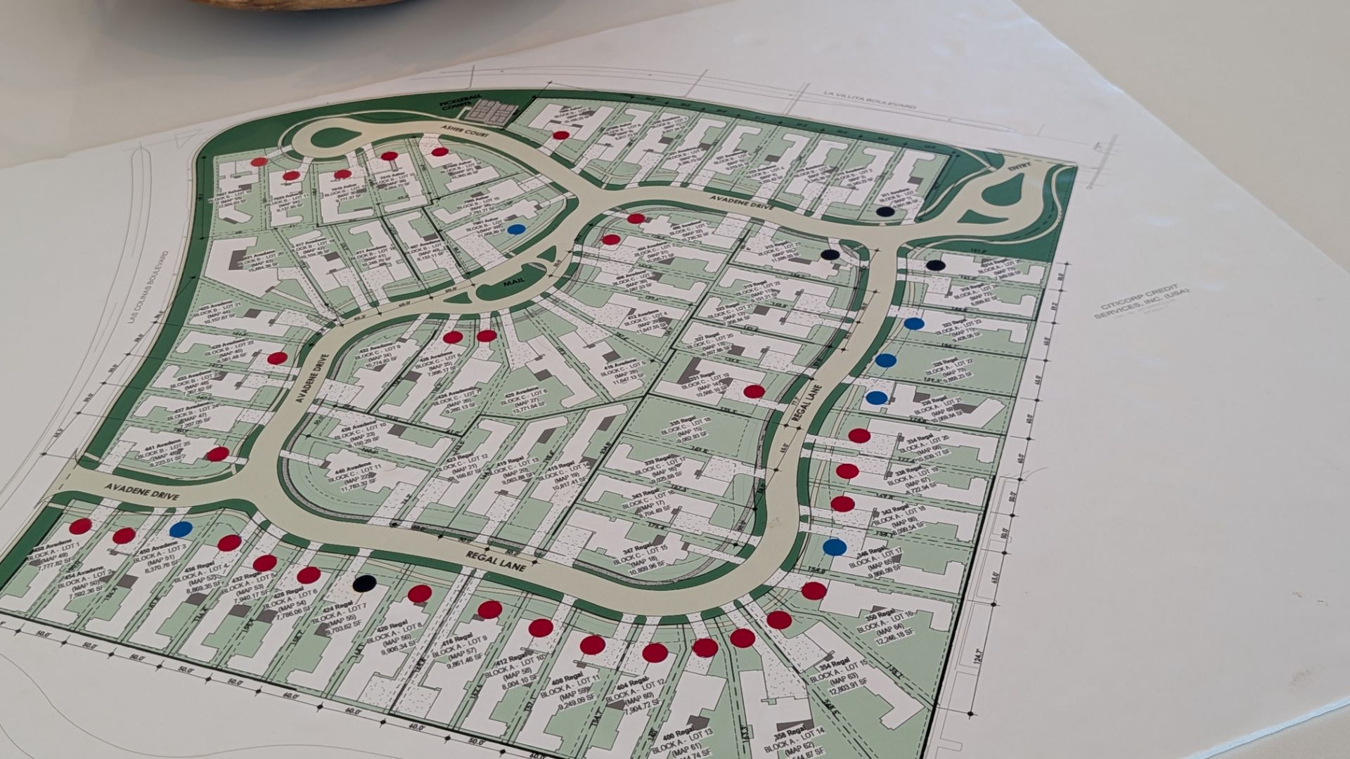 Blueprint of a planned community with roads, buildings, and colored dots marking locations.
