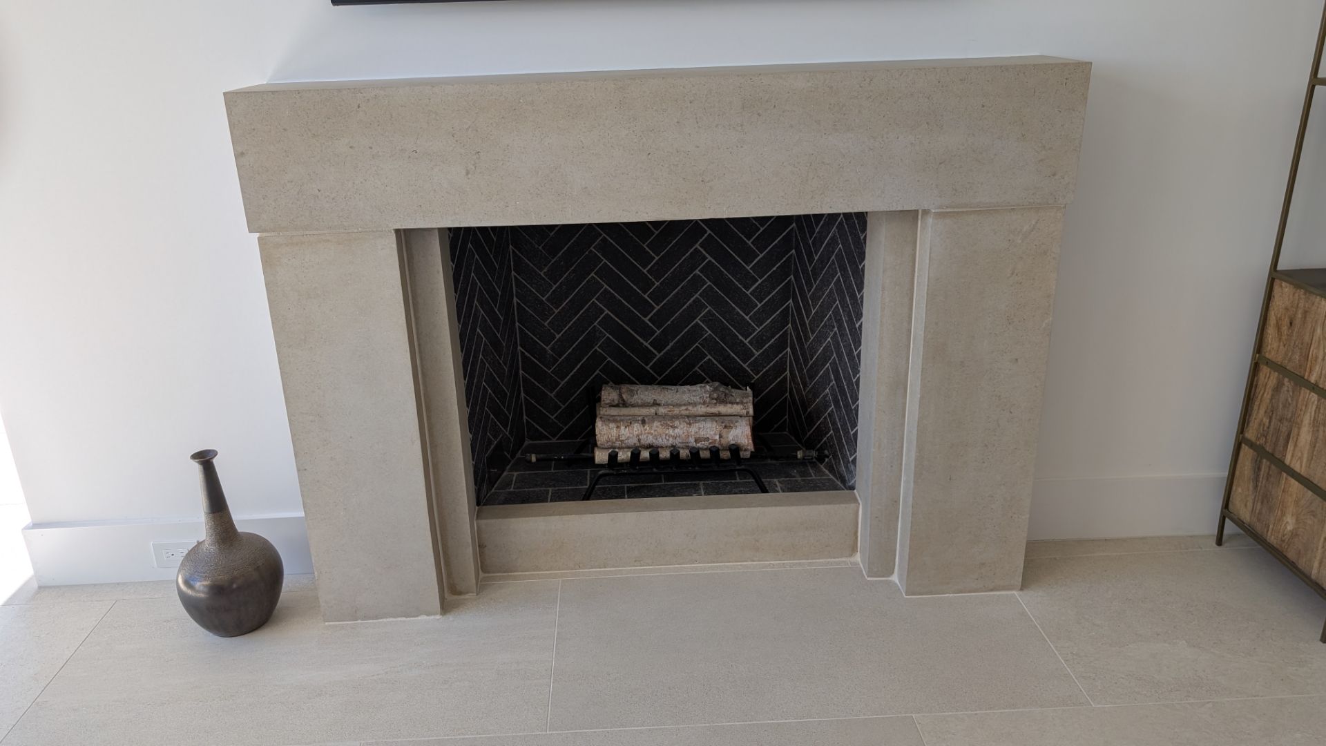 Fireplace with gray stone surround and black herringbone tile interior.