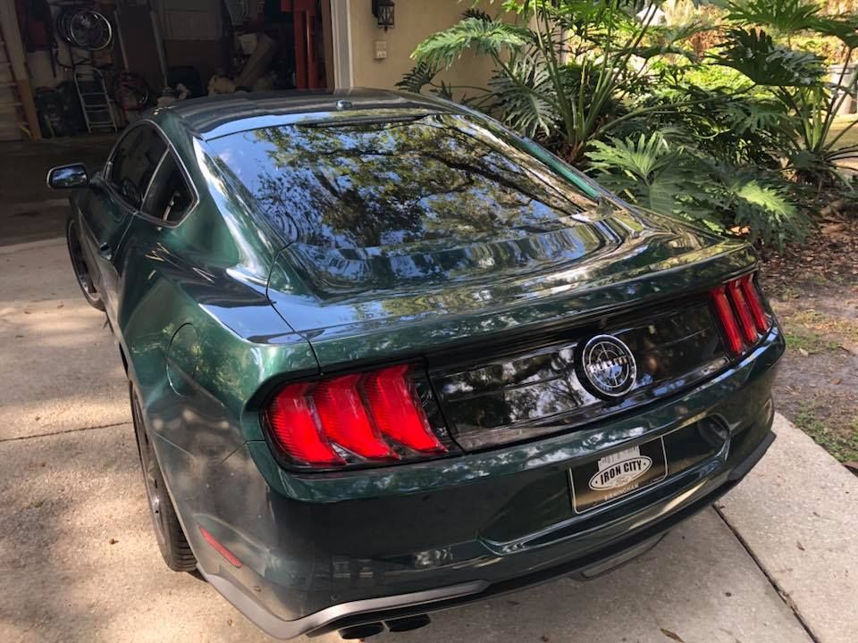 A green ford mustang is parked in front of a garage.