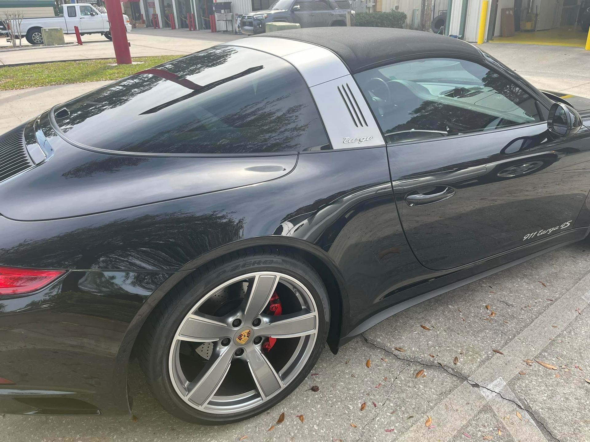 A black porsche targa is parked on the side of the road