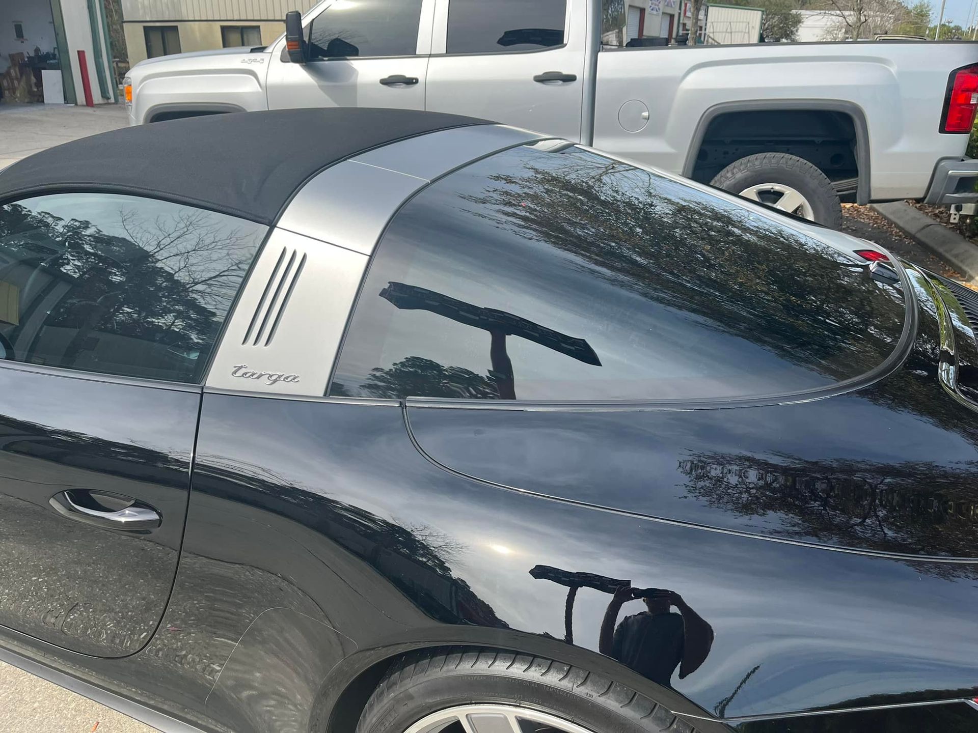 A black sports car is parked next to a silver truck