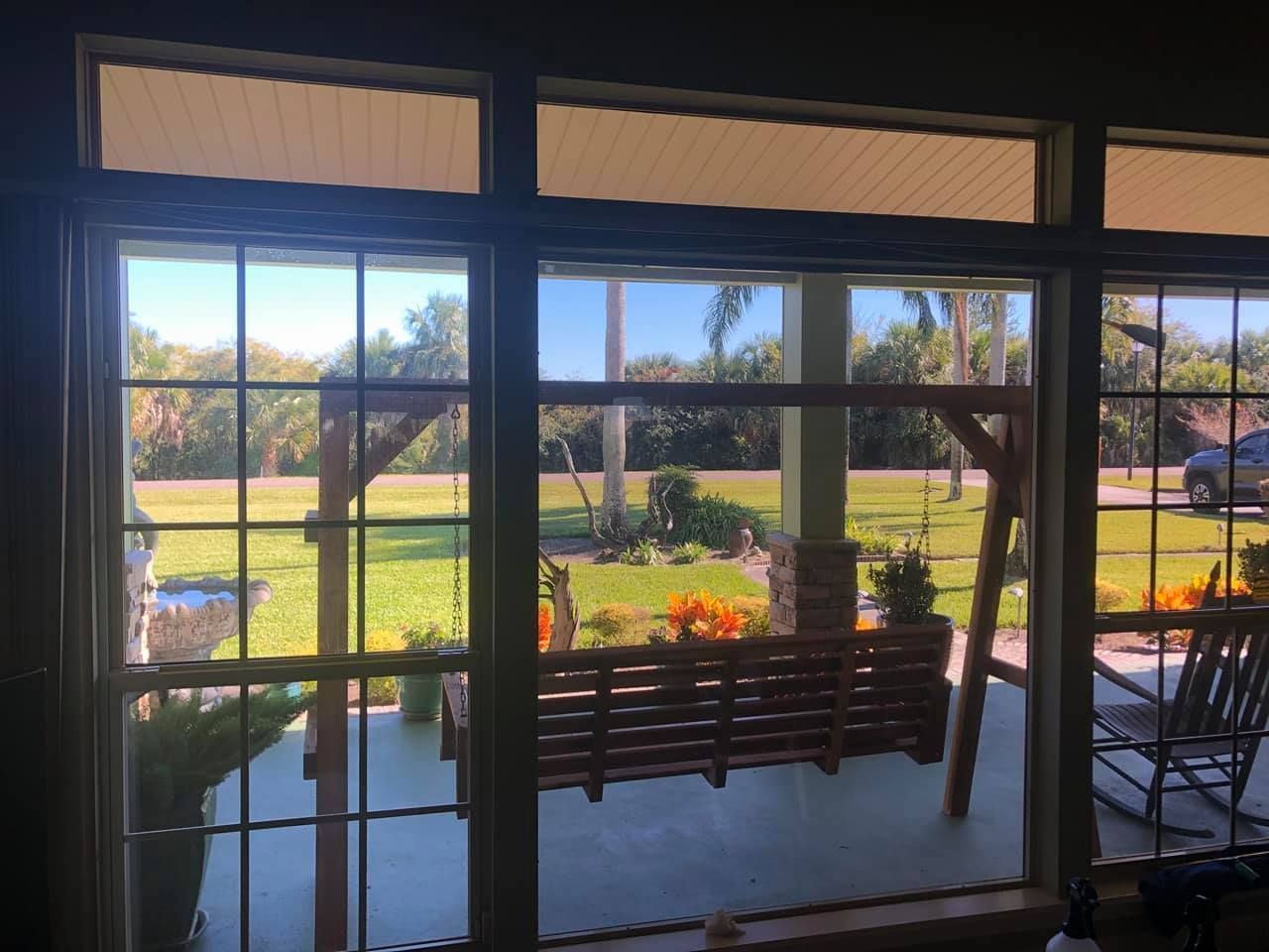 A porch swing is visible through the window of a house.