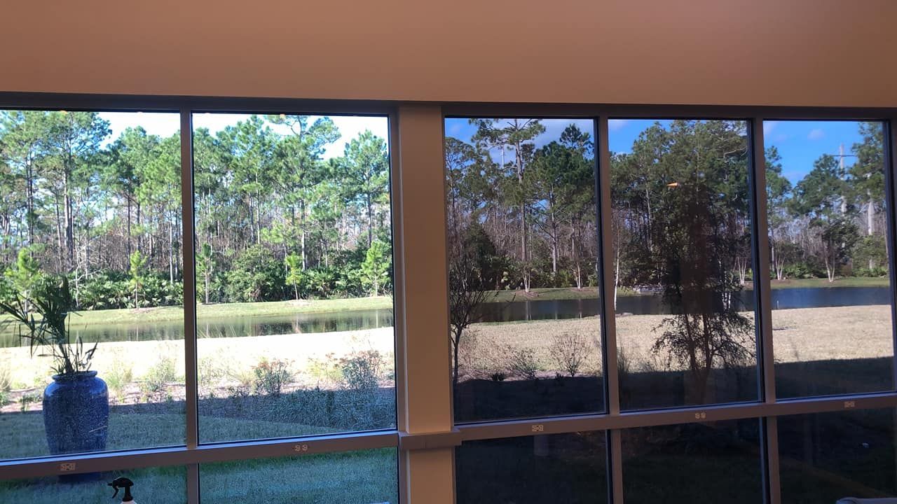 A room with a lot of windows and a view of trees and a lake.