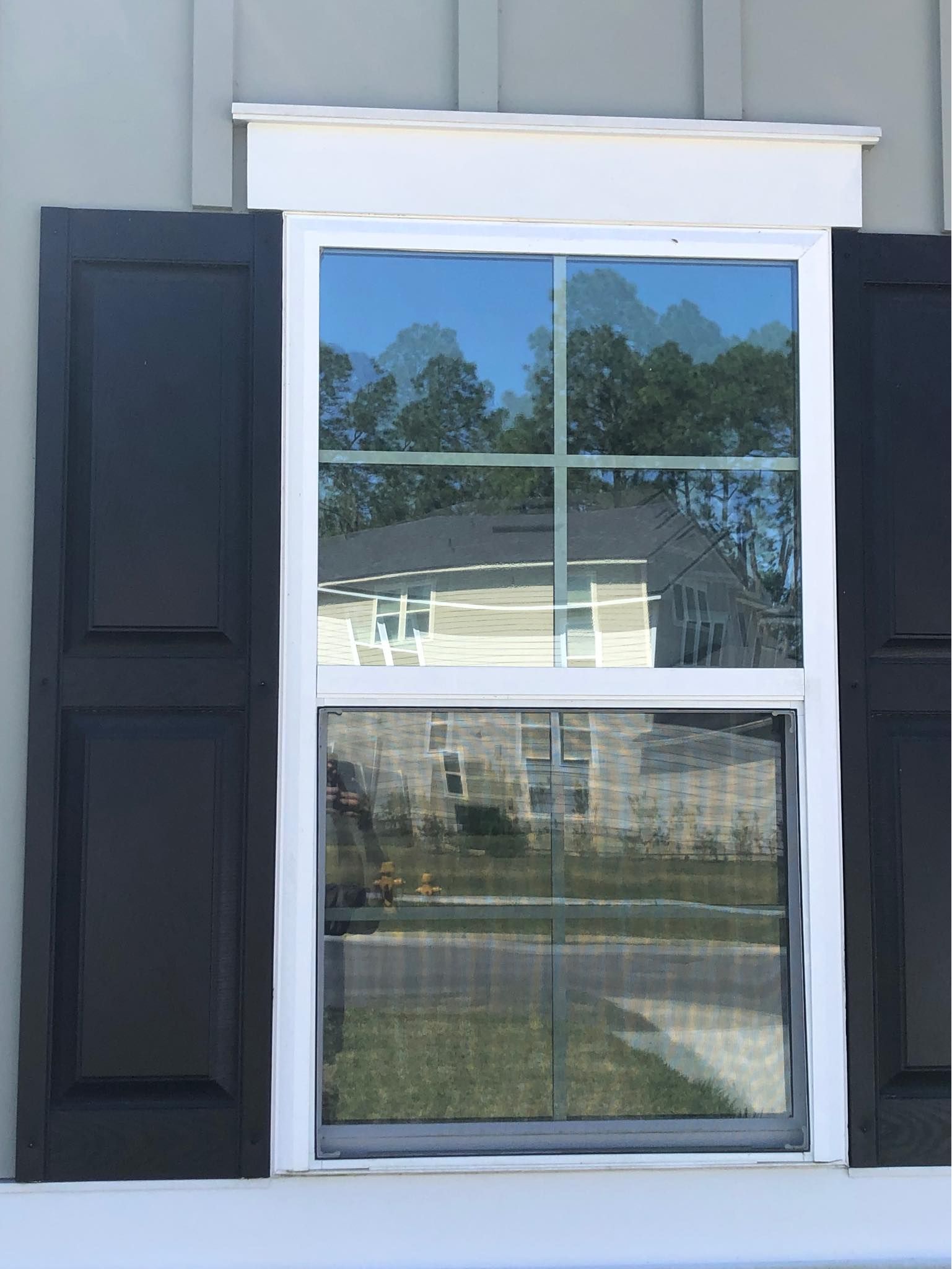 A white window with black shutters on a house.