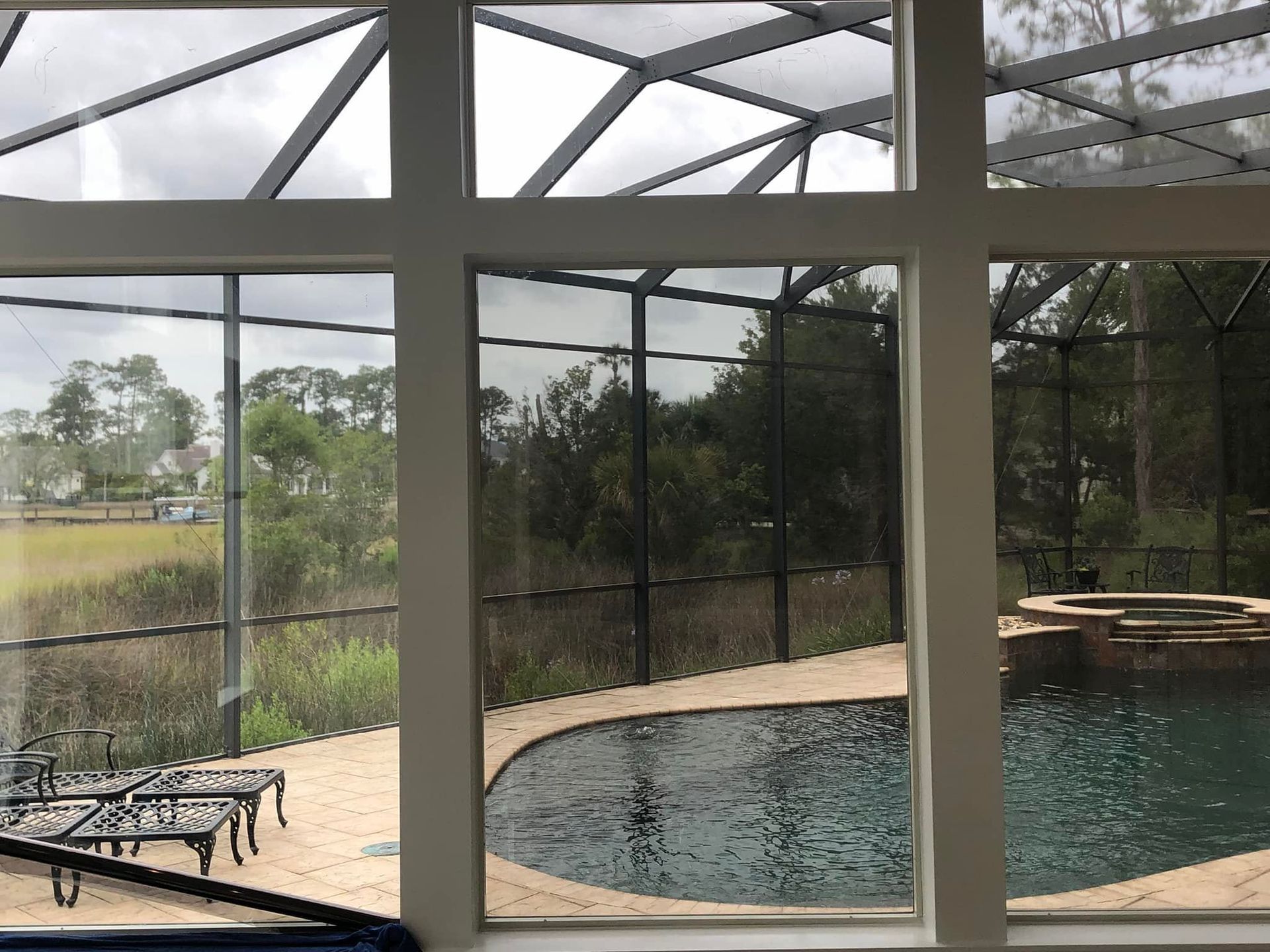 A view of a swimming pool through a screened in area.