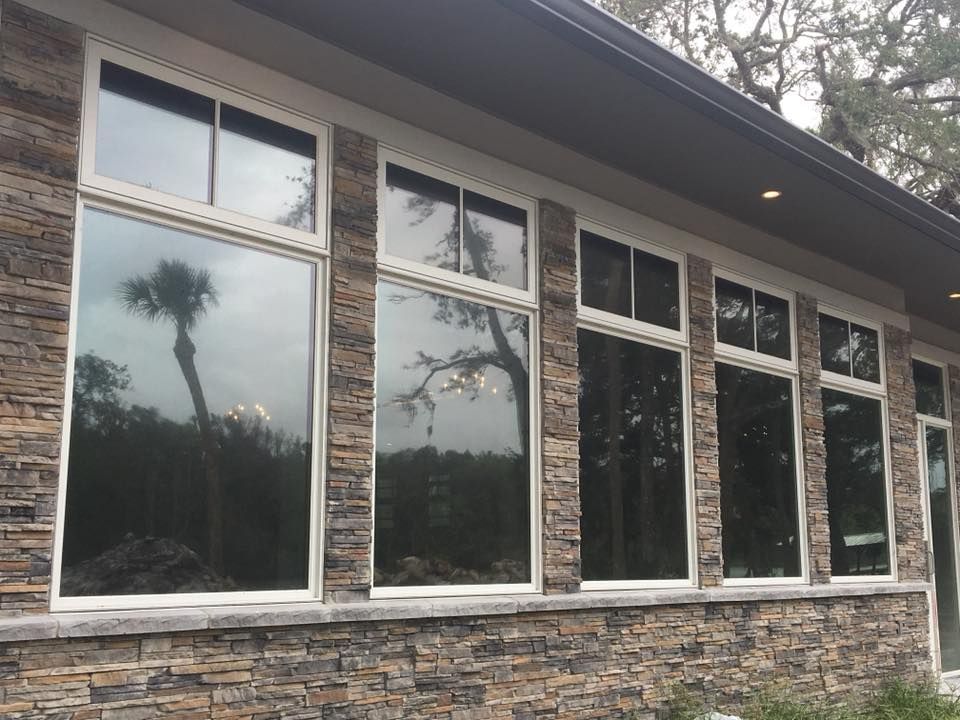 A house with a lot of windows and a stone wall.