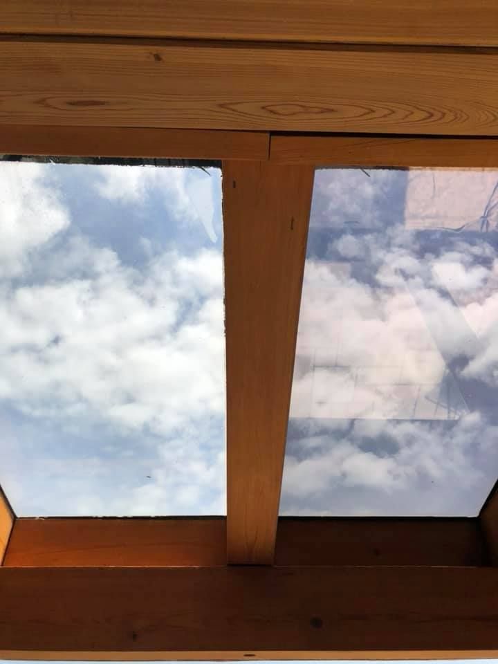 The sky is reflected in the window of a wooden structure.
