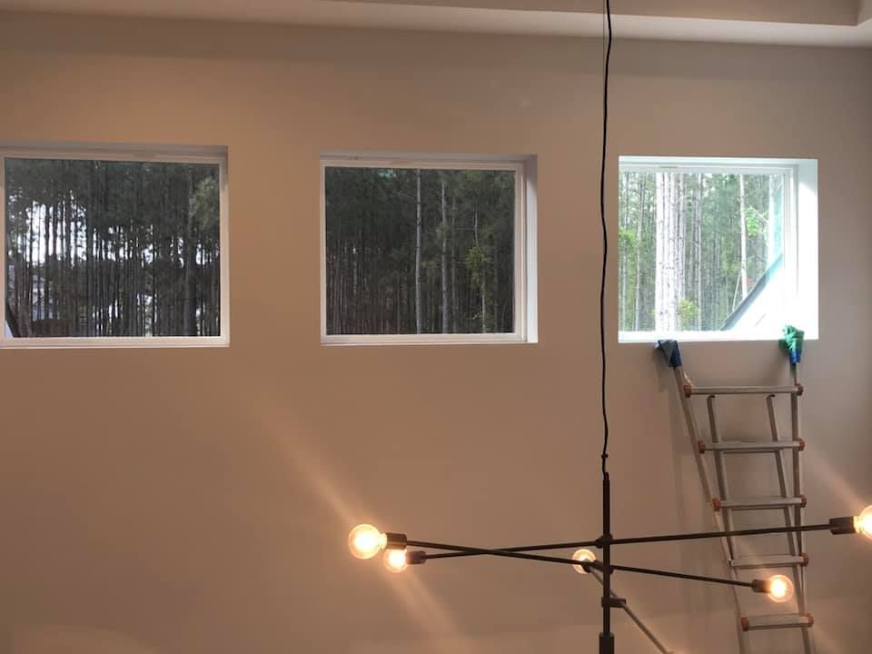 A room with three windows and a ladder hanging from the ceiling