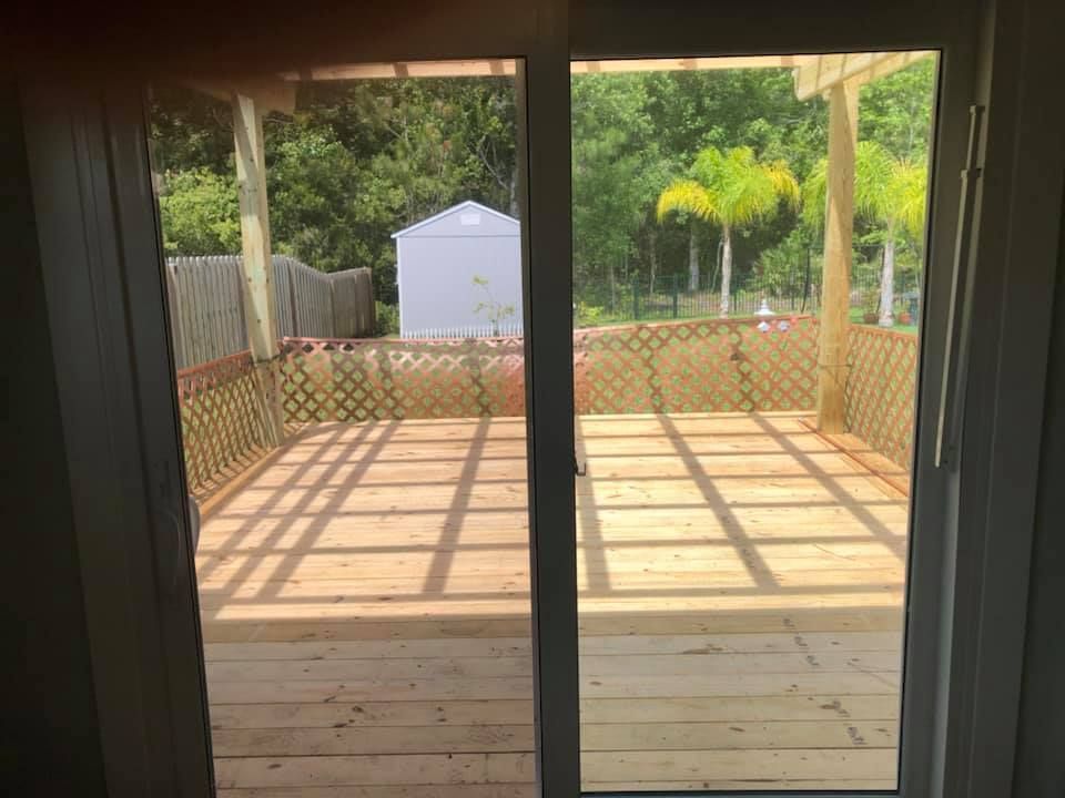 A view of a wooden deck through a sliding glass door.