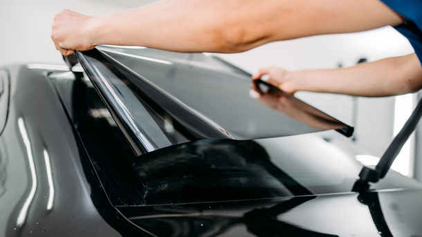 A person is applying tinted glass to a car window.