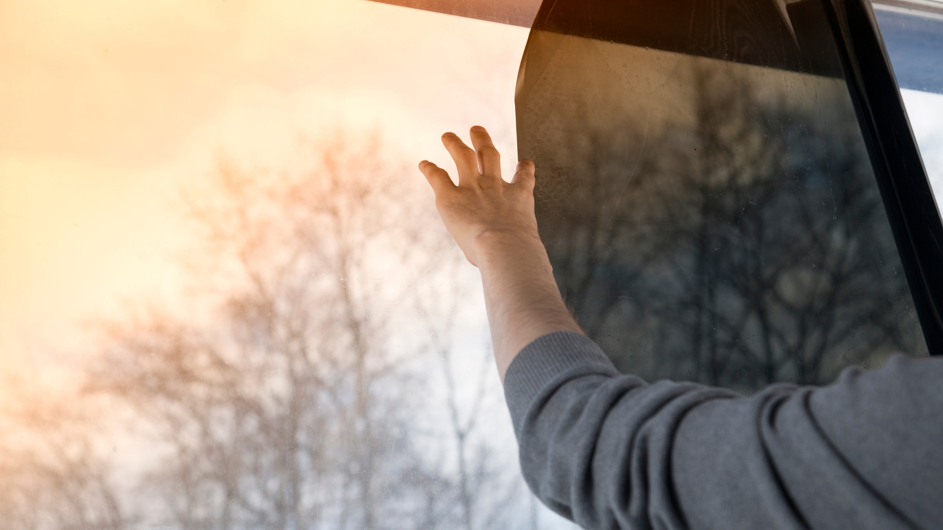 A person is touching a window with their hand.